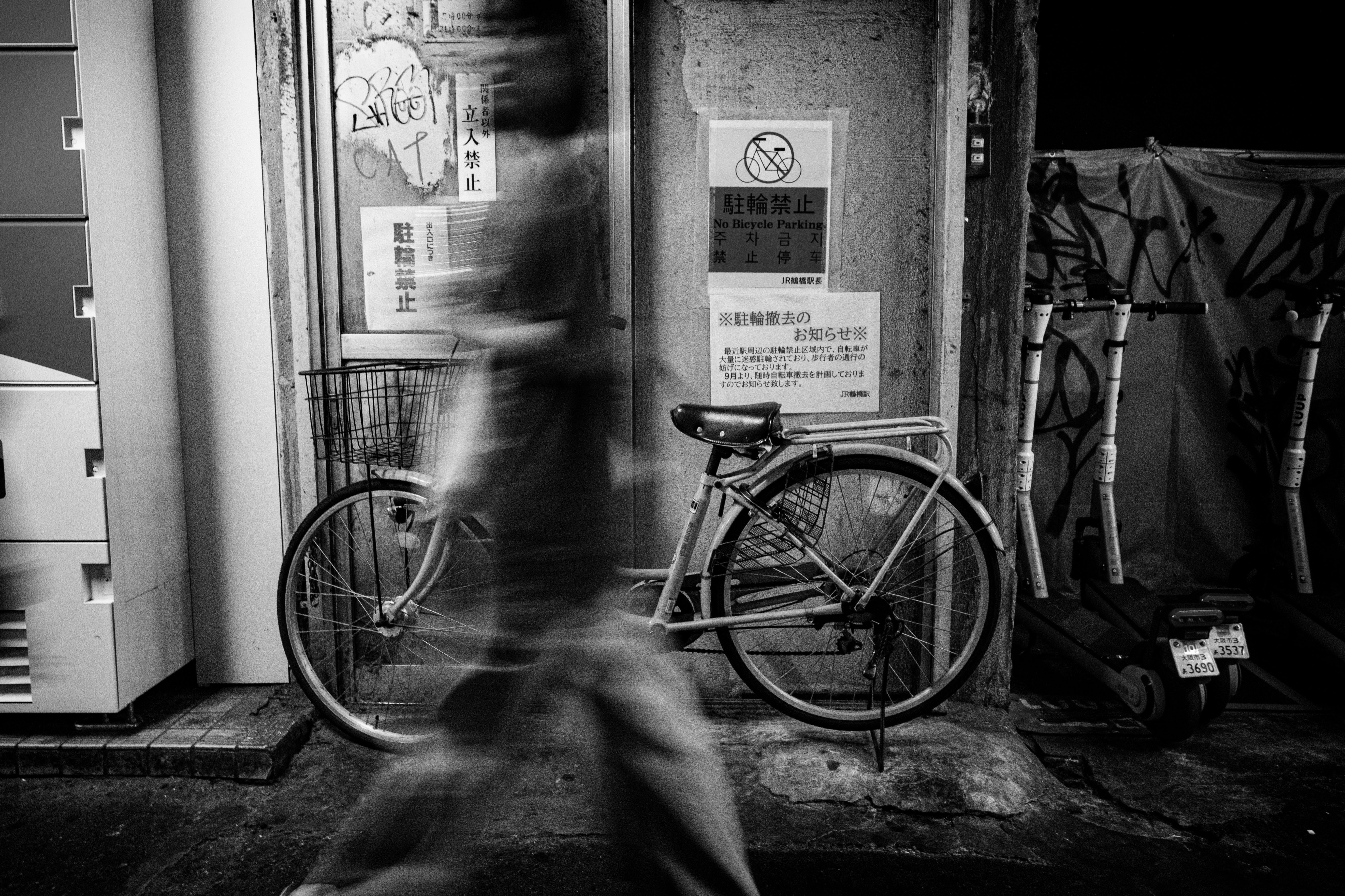 駐輪禁止の掲示と自転車が並ぶ路地のモノクロ