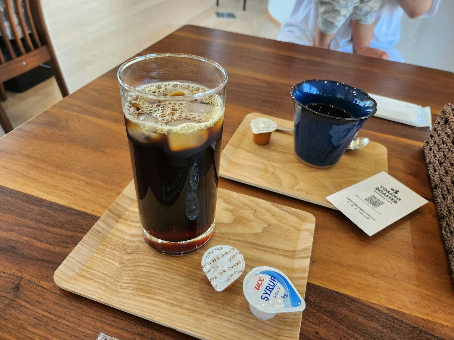 Iced coffee with cream container on a wooden tray in a café