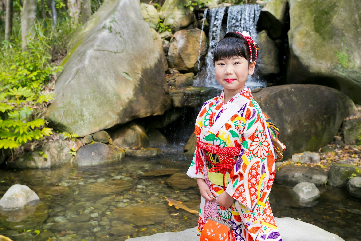 穿着五彩缤纷和服的女孩站在瀑布前