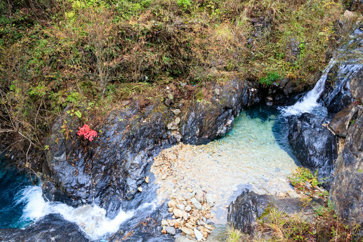 一幅峡谷的风景，蓝色水流在岩石间流动，有一个小沙滩