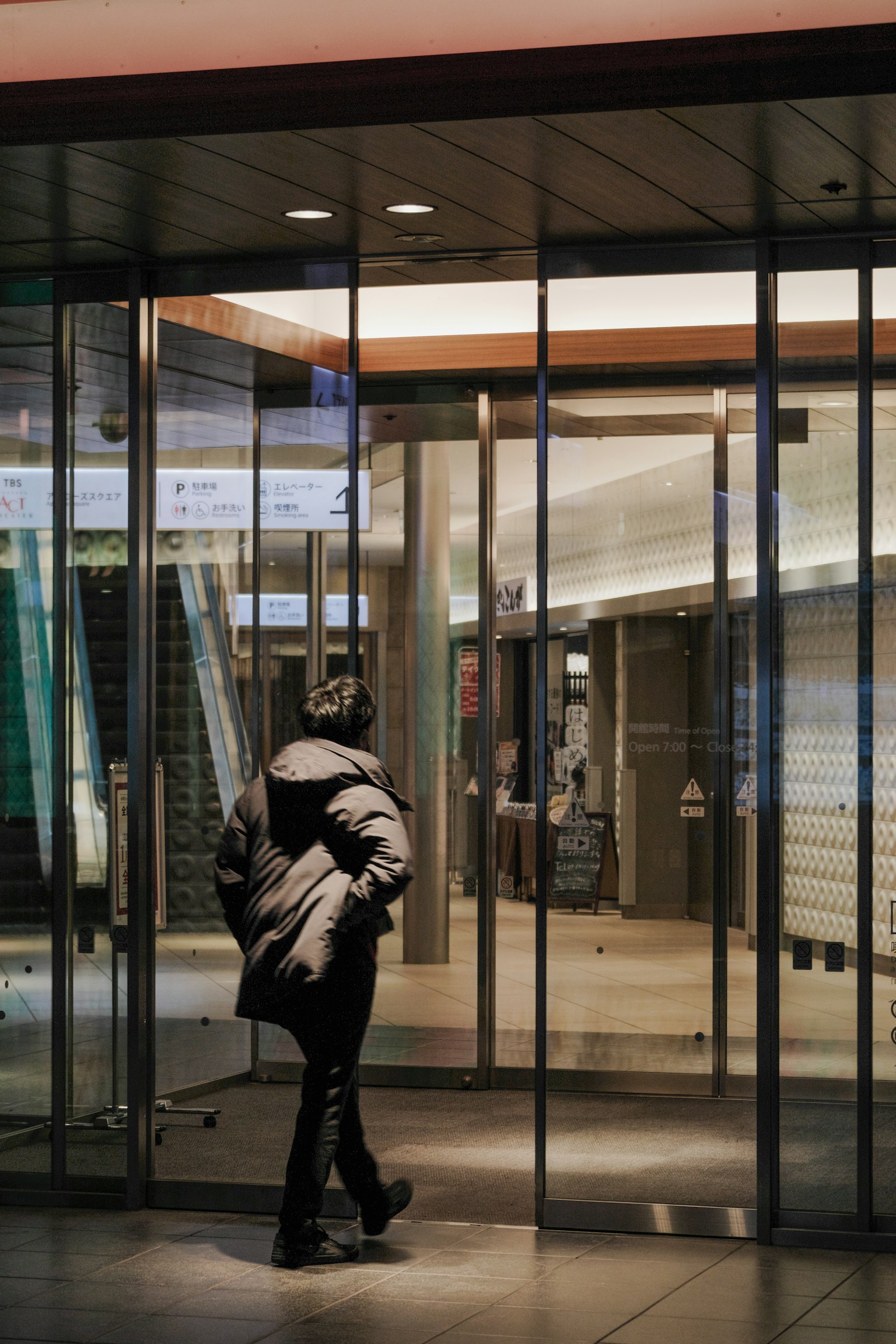 Una persona caminando a través de puertas de vidrio hacia el interior de un edificio moderno