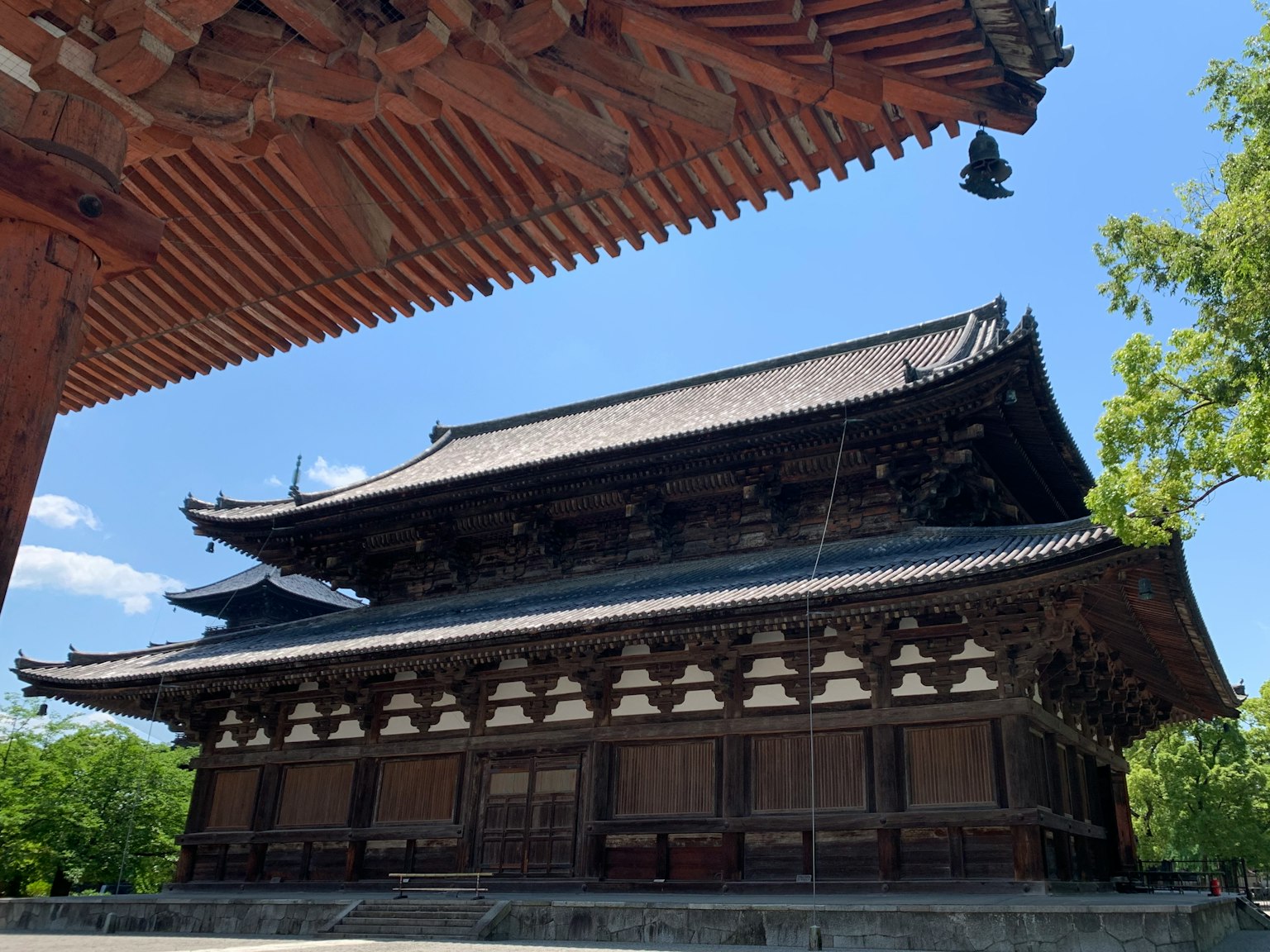 Äußeres eines Tempels im japanischen Architekturstil unter blauem Himmel mit detailliertem Dach und Struktur