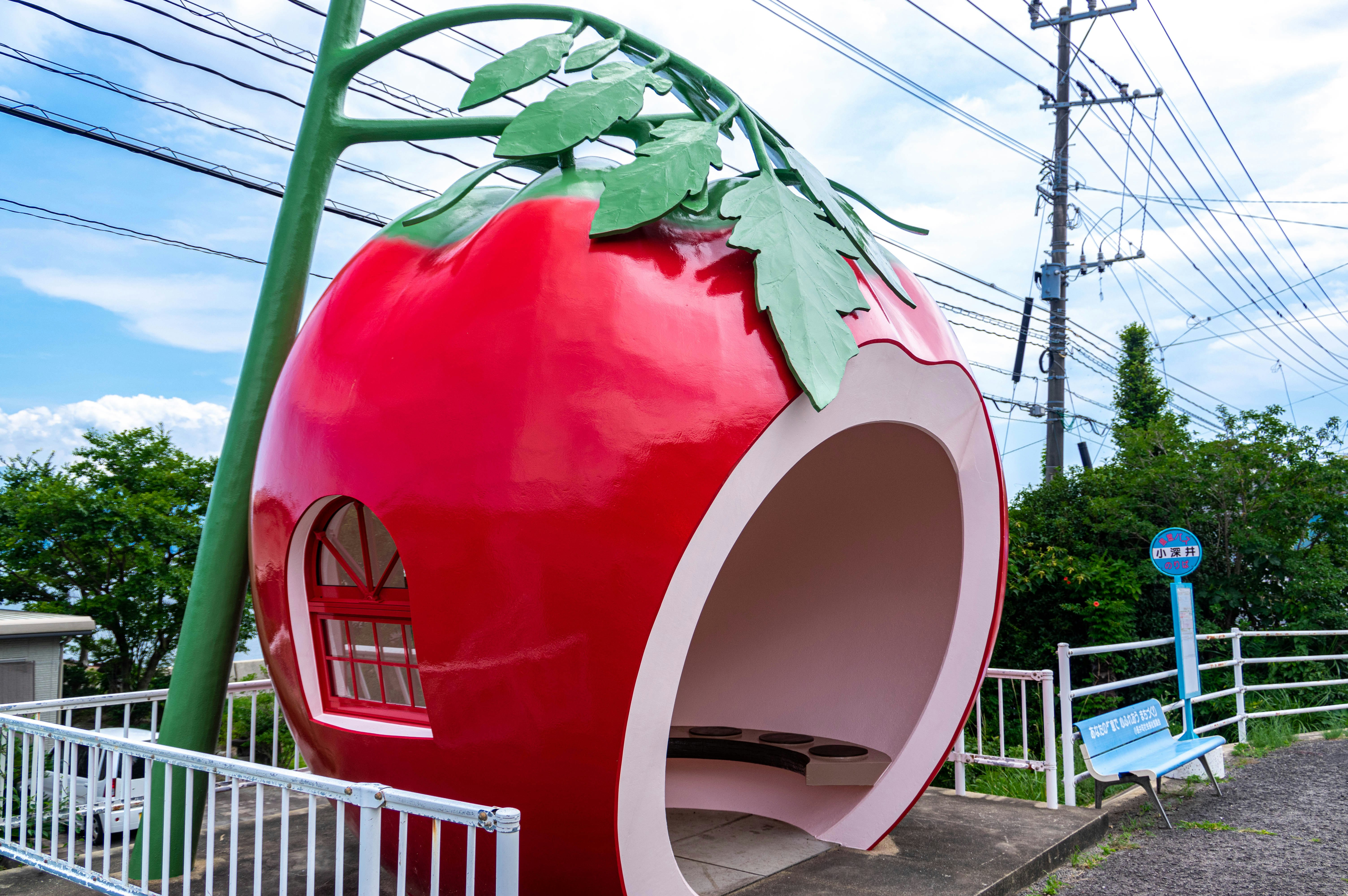 赤い丸い遊具のトンネルと緑の葉の装飾がある屋外の遊び場