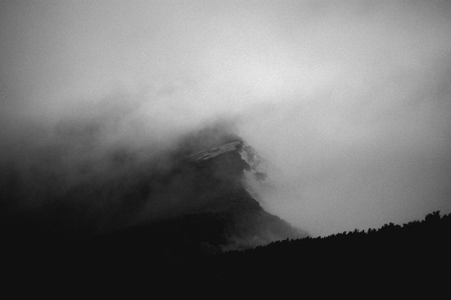 Silueta de una montaña envuelta en niebla en una imagen en blanco y negro