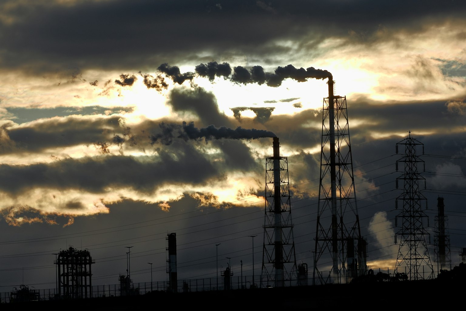 Factory smokestacks emitting smoke against a cloudy sky