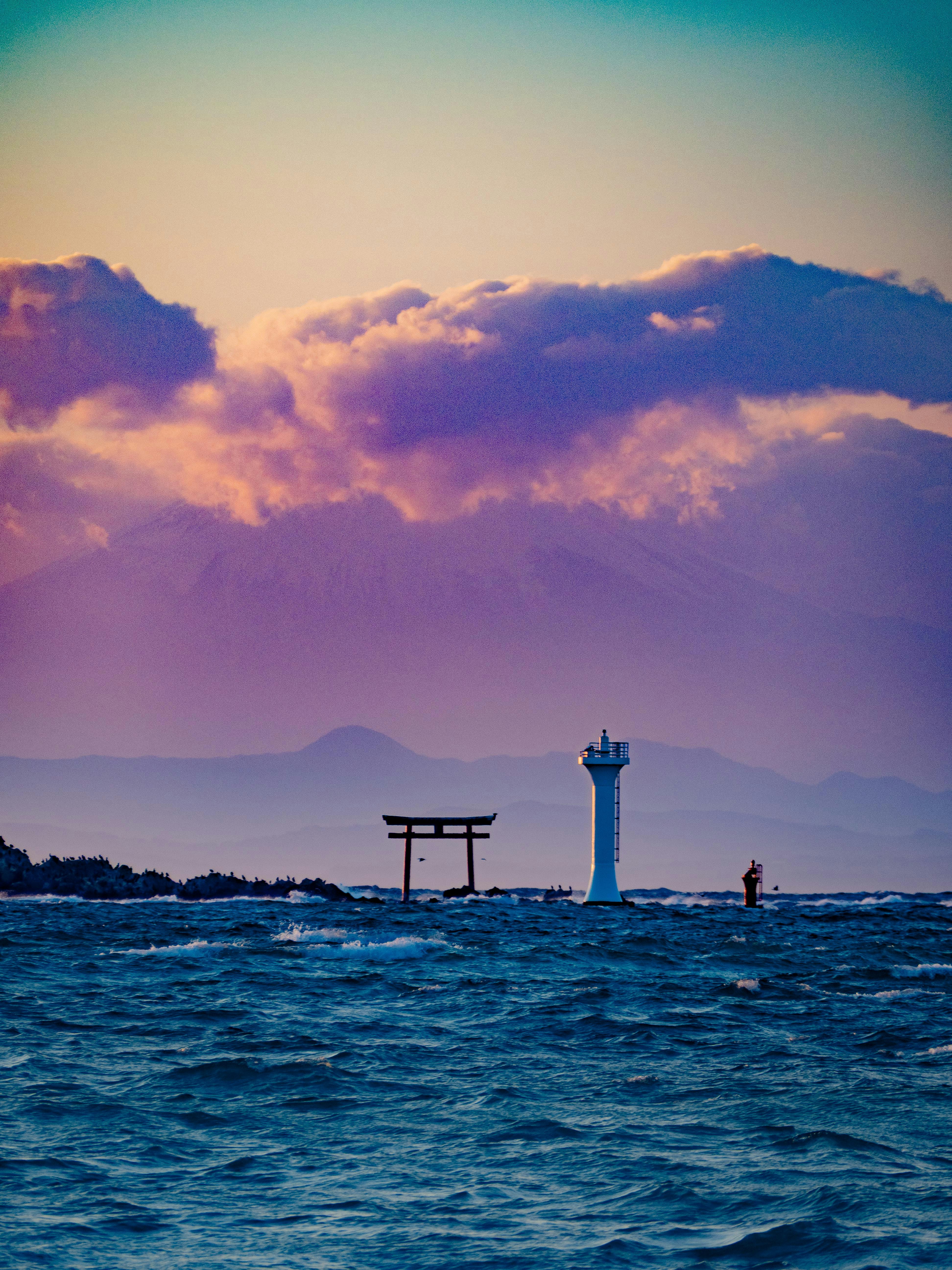 tramonto sul mare con un faro e piccole imbarcazioni in lontananza