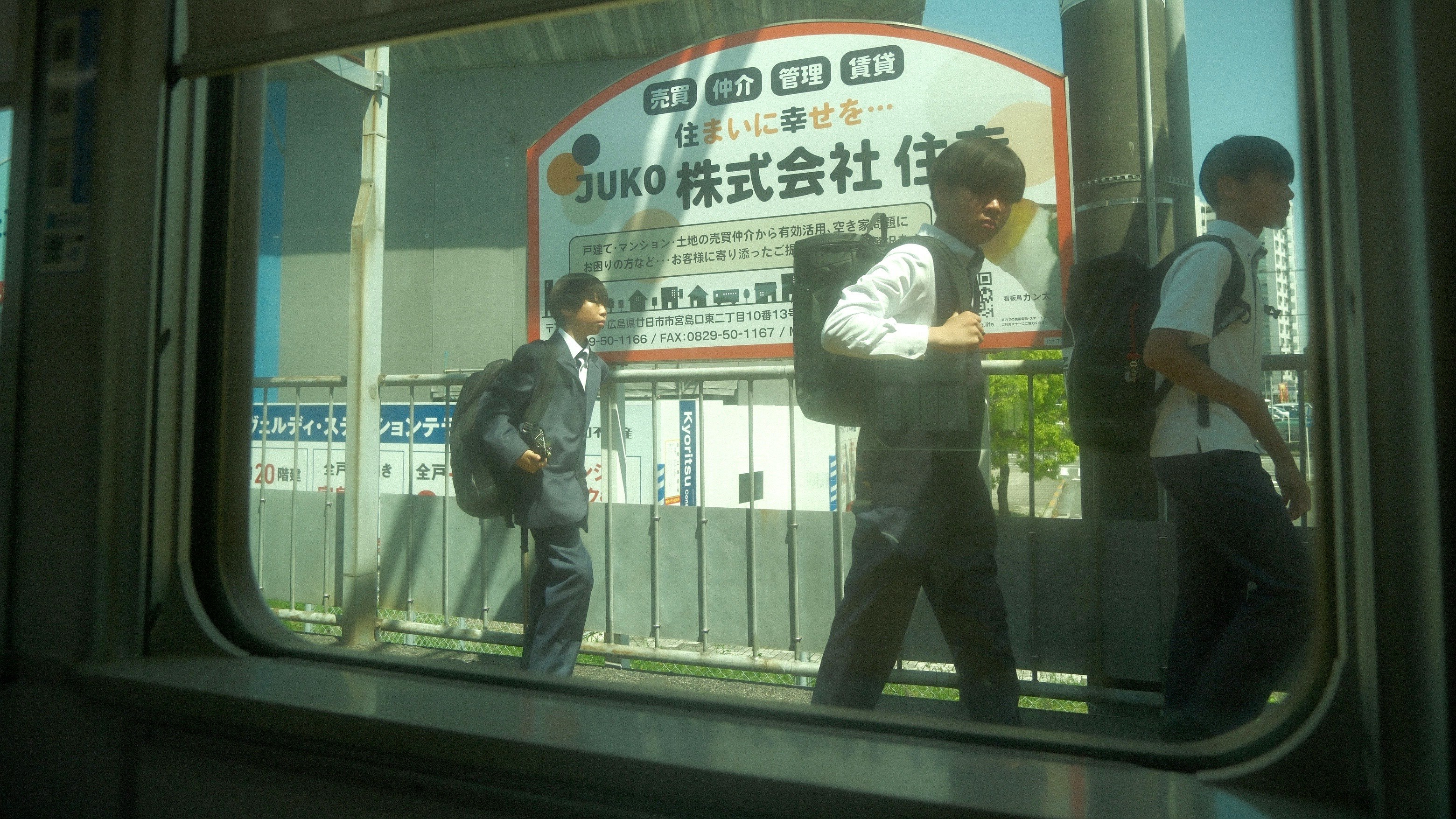 電車の窓から見える通勤者と駅のホーム風景