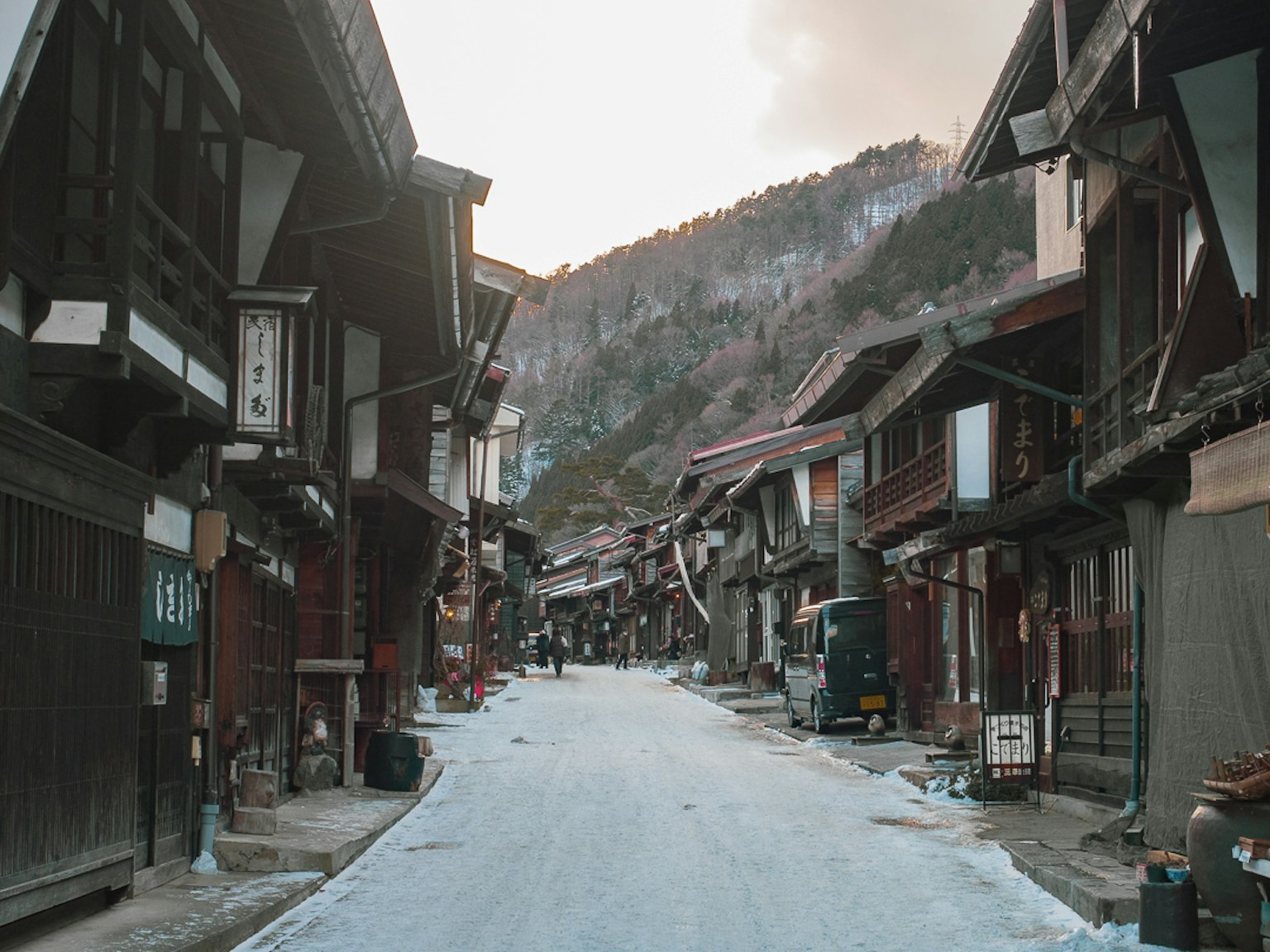 被雪覆蓋的傳統小鎮街道，木建築和山脈