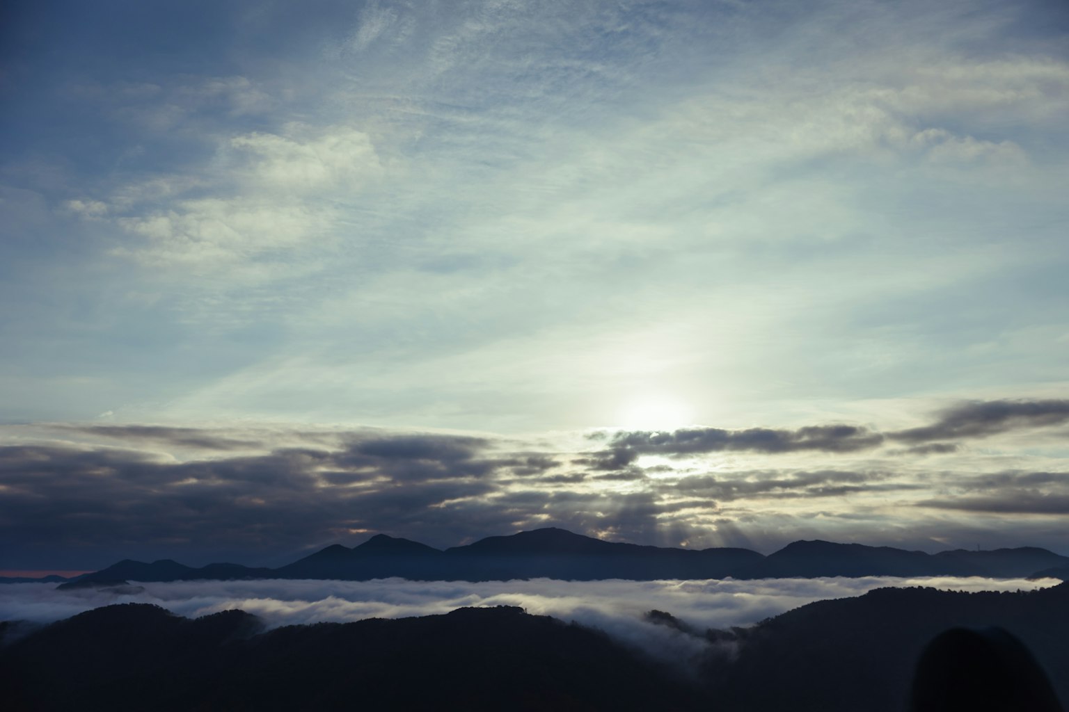 Silhouette de montagnes au-dessus d'une mer de nuages sous un ciel bleu