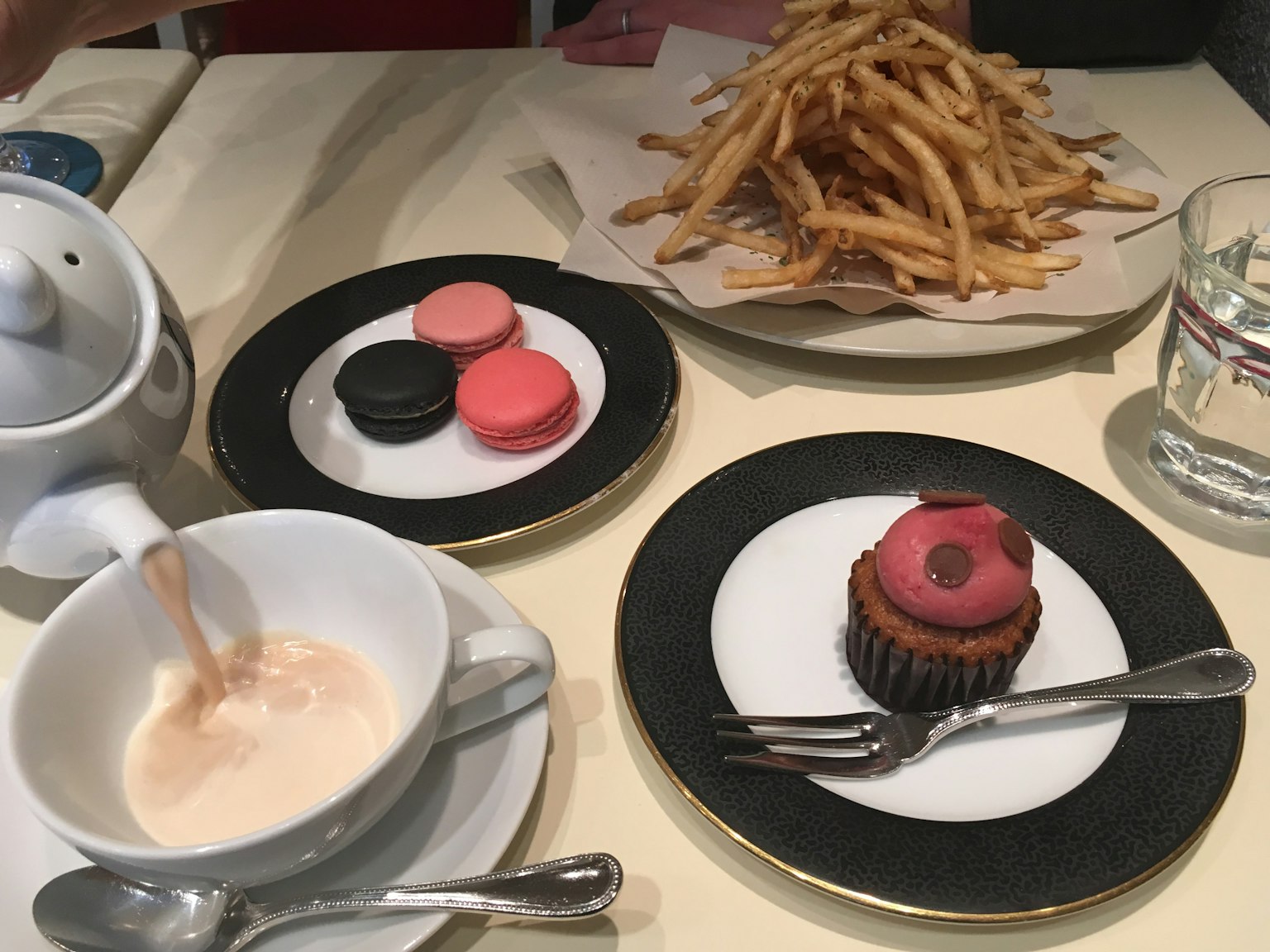 Bàn với cốc chứa đồ uống màu nâu bánh macaron bánh cupcake và đĩa khoai tây chiên