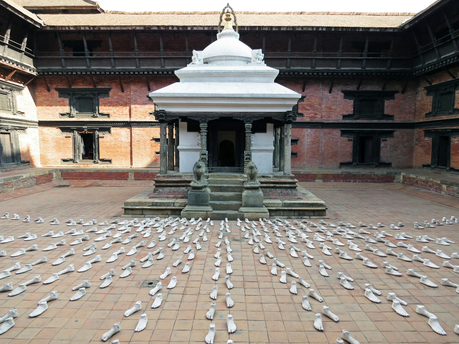 中央有白色寺廟，周圍地面上有鞋子