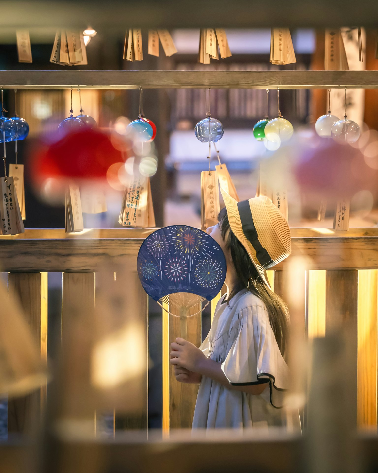 Ein Mädchen bewundert Windspiele an einem Sommerfeststand