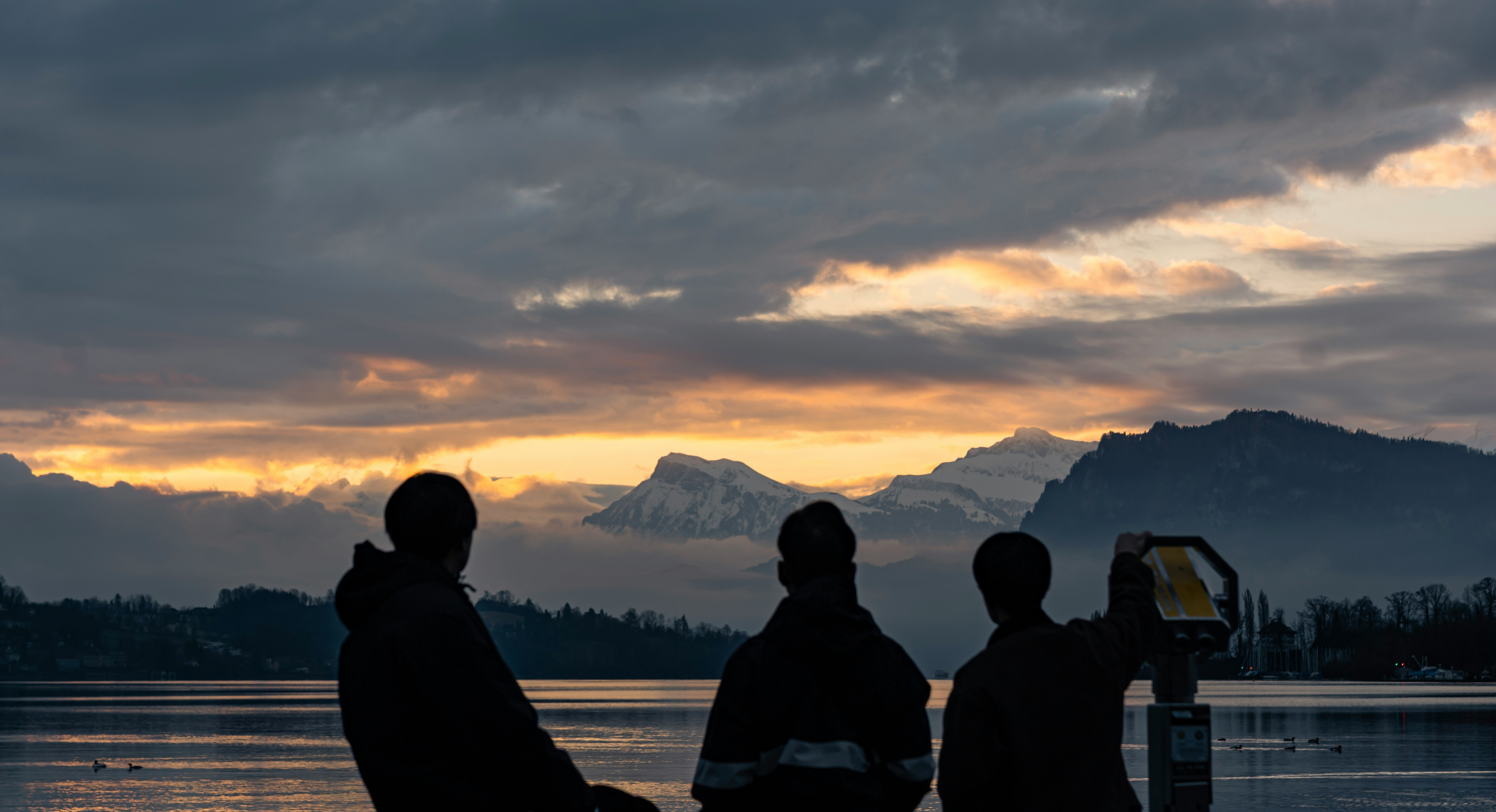 Silhuetas de personas contemplando el amanecer sobre el lago de Lucerna en Suiza
