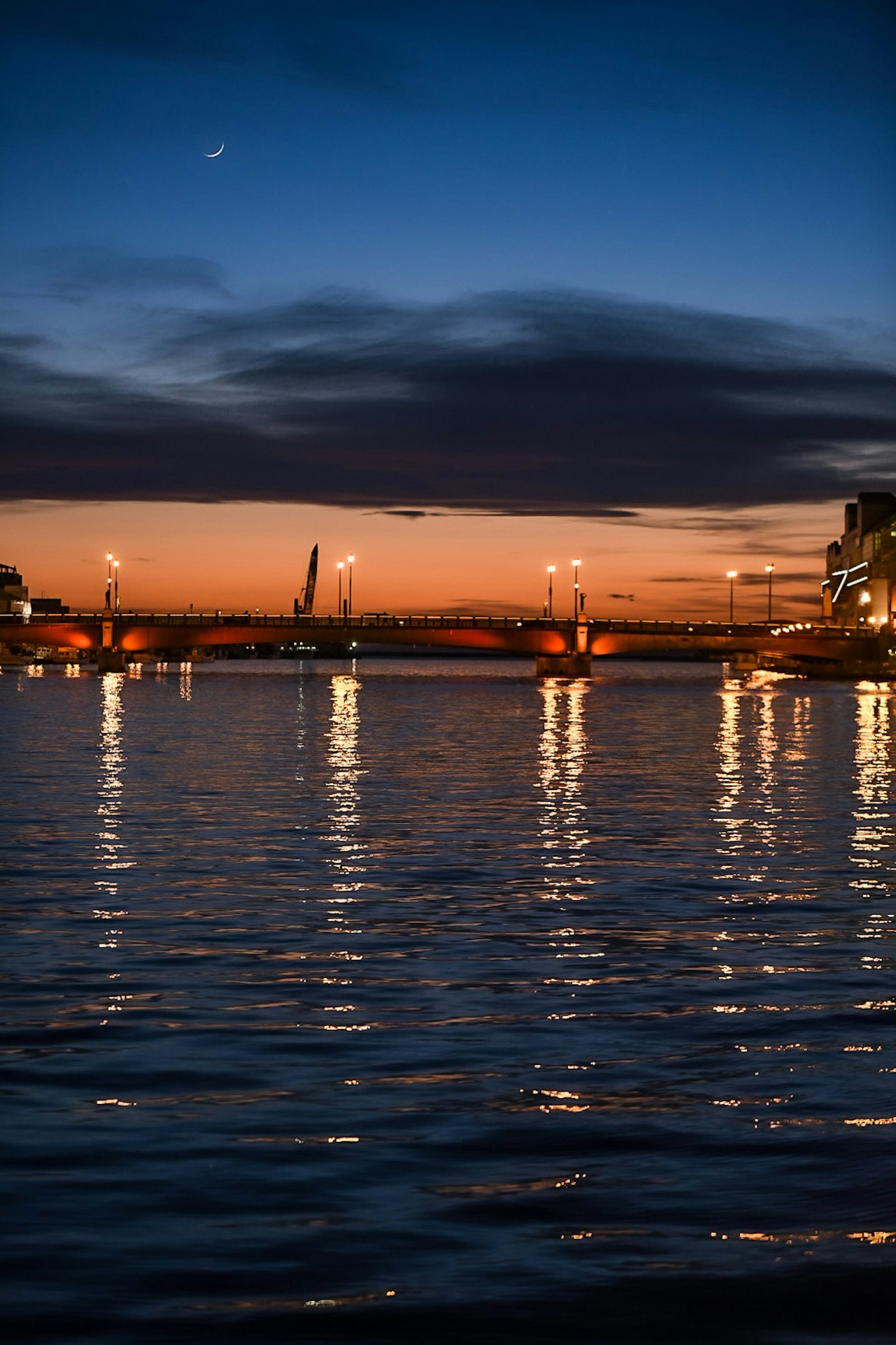 Scena di fiume al crepuscolo che riflette le luci della città Superficie d'acqua scintillante e cielo scuro