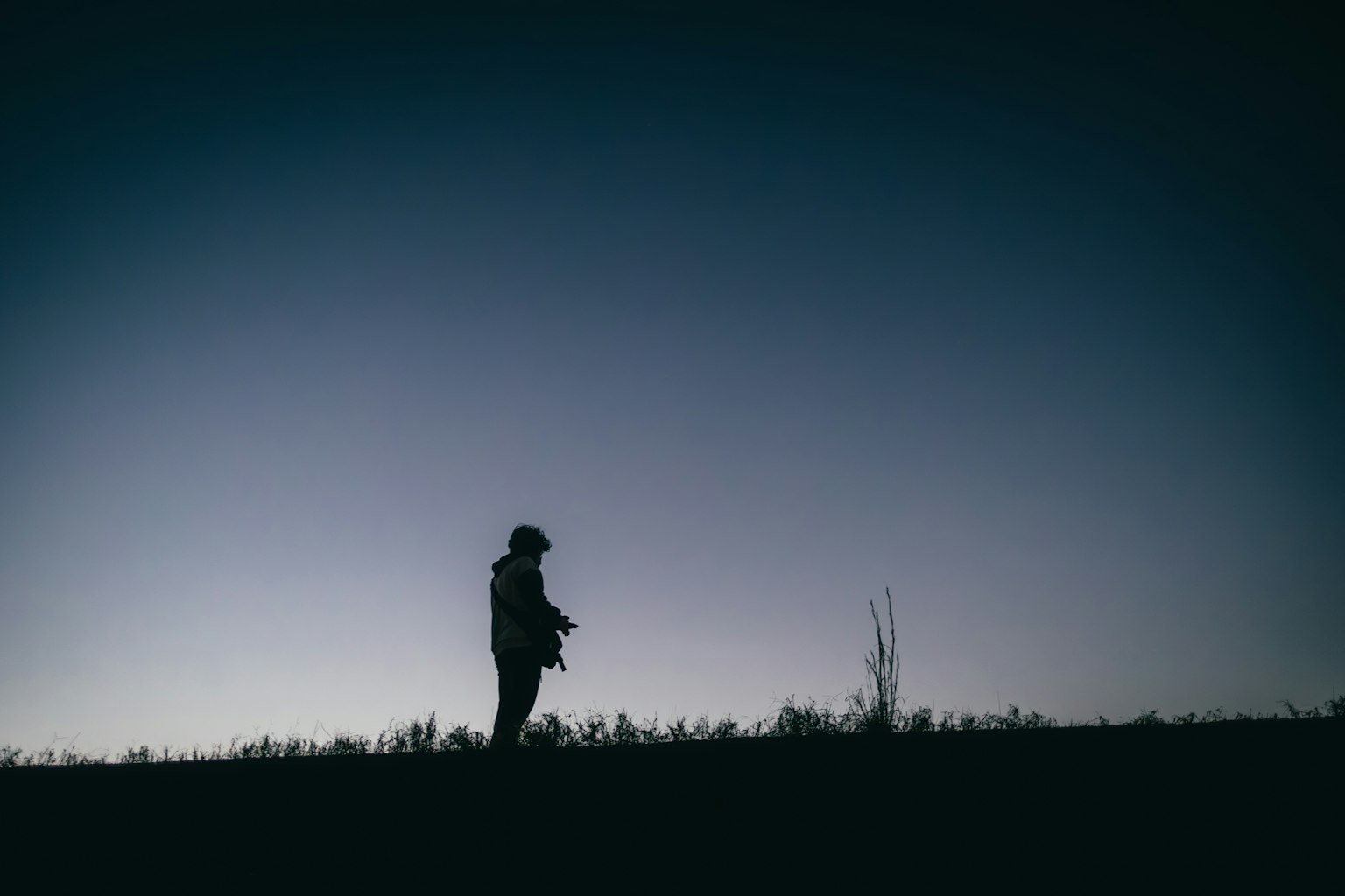 Silhouette d'une personne se tenant au crépuscule contre un ciel dégradé