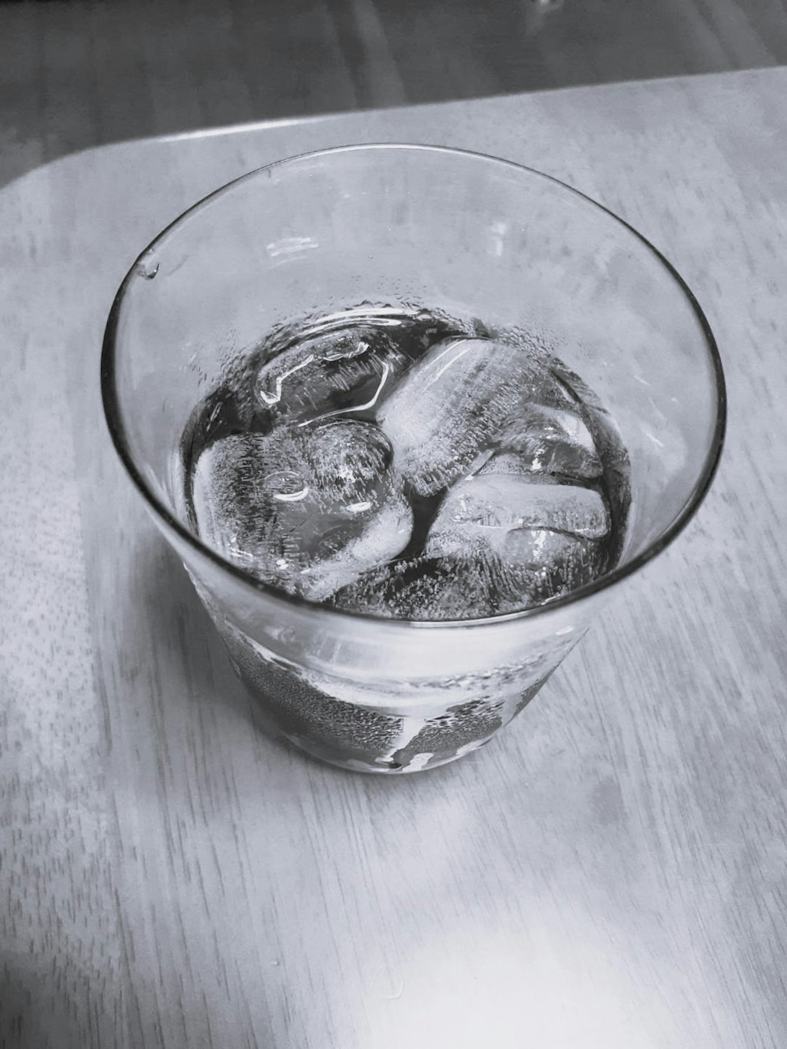 Un verre transparent rempli de glace et d'une boisson foncée