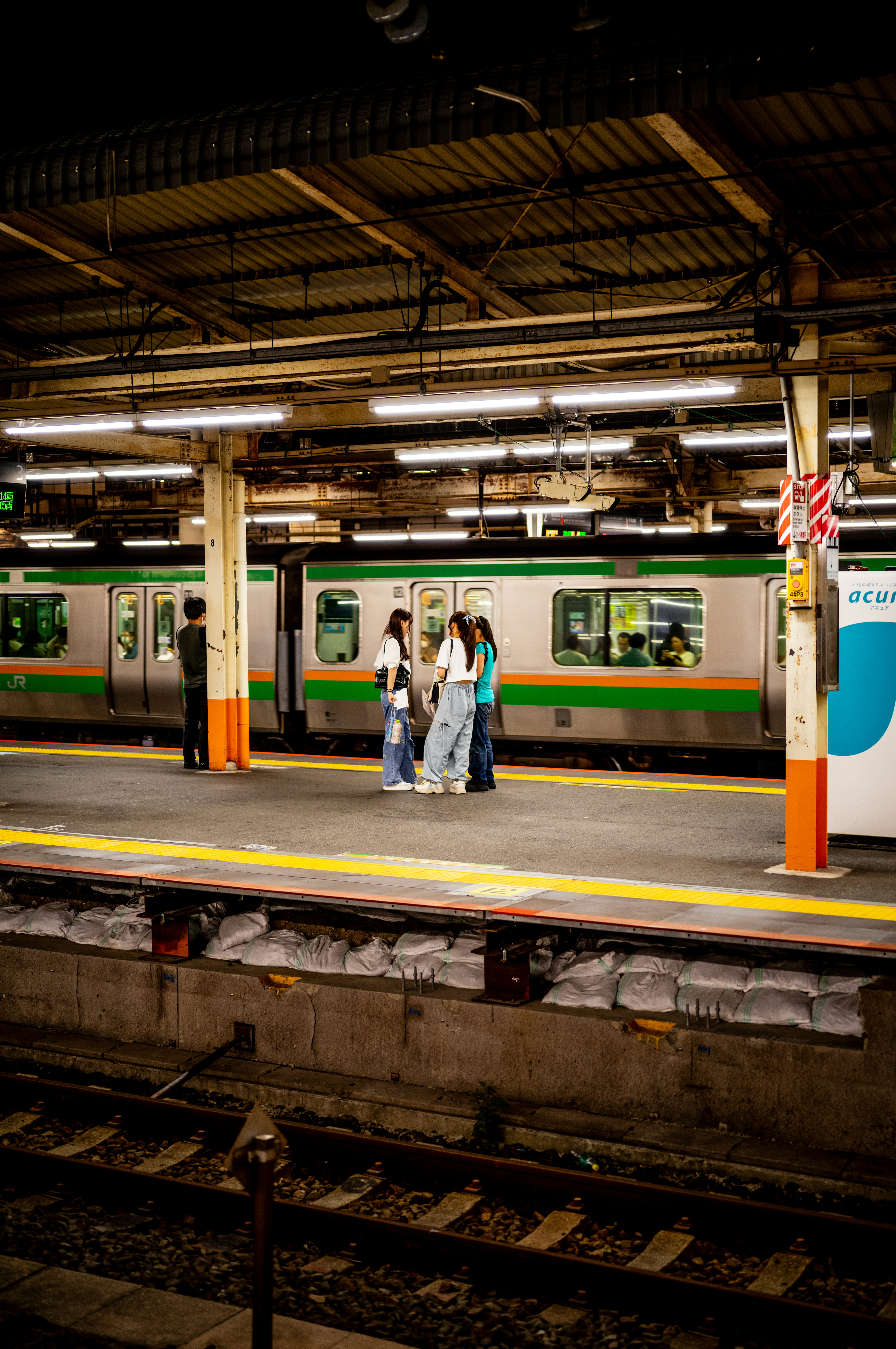 夜の駅ホームで電車を待つ人々のある風景