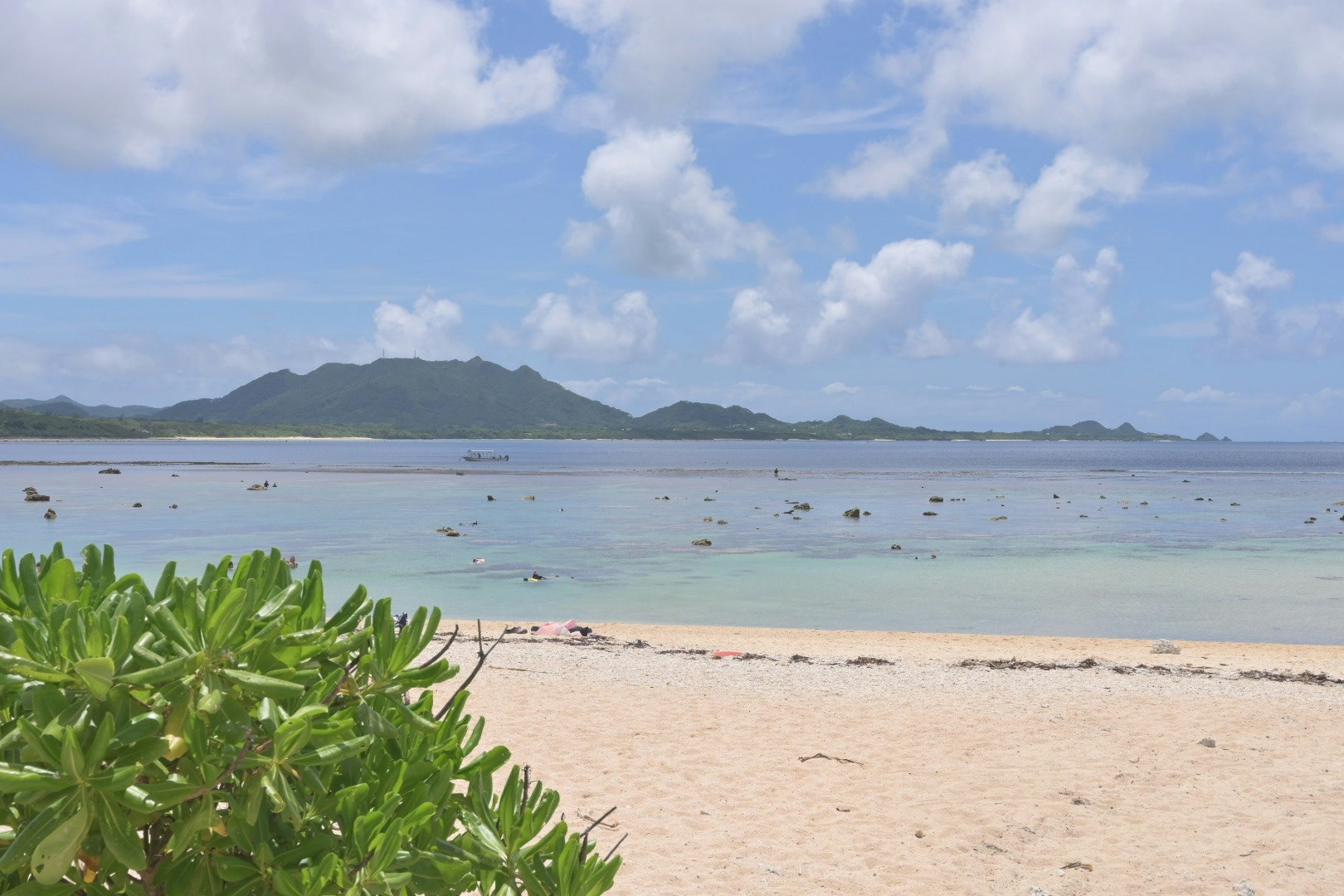 海辺の砂浜と遠くの島々が見える夏の海水浴風景