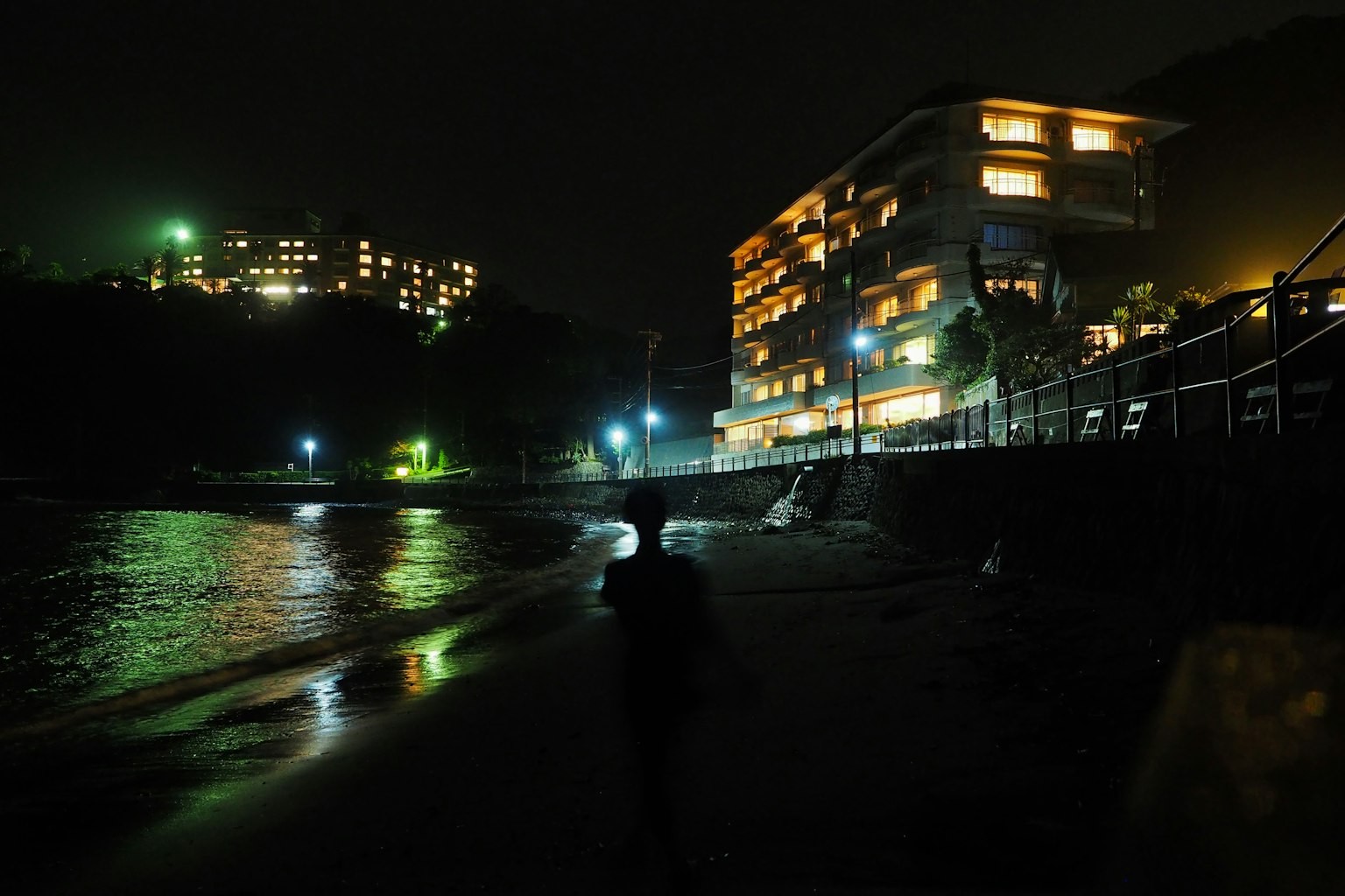 夜晚海滩上的人和亮灯的建筑