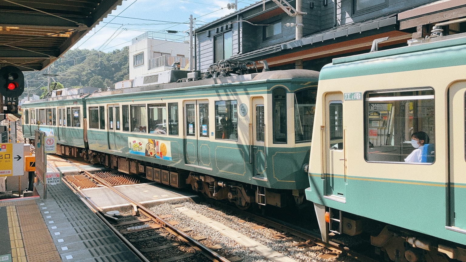Tàu xanh dừng lại ở ga với các tòa nhà phía sau