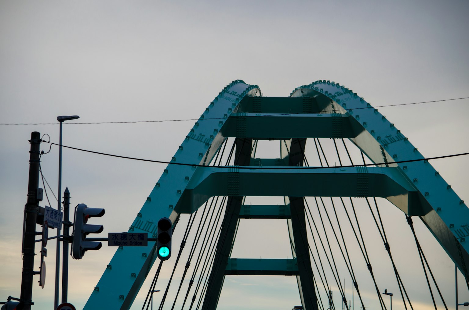 Estructura superior de un puente arqueado azul con semáforos