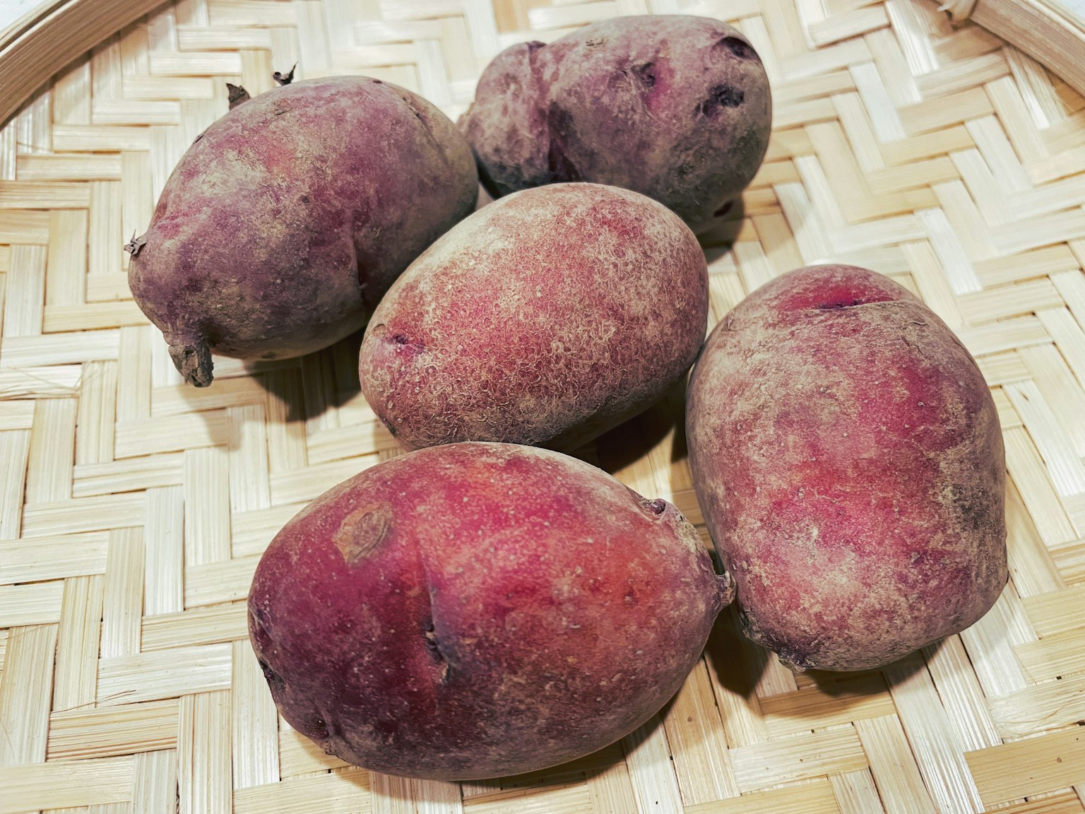 Patate dolci viola disposte in un cesto di bambù