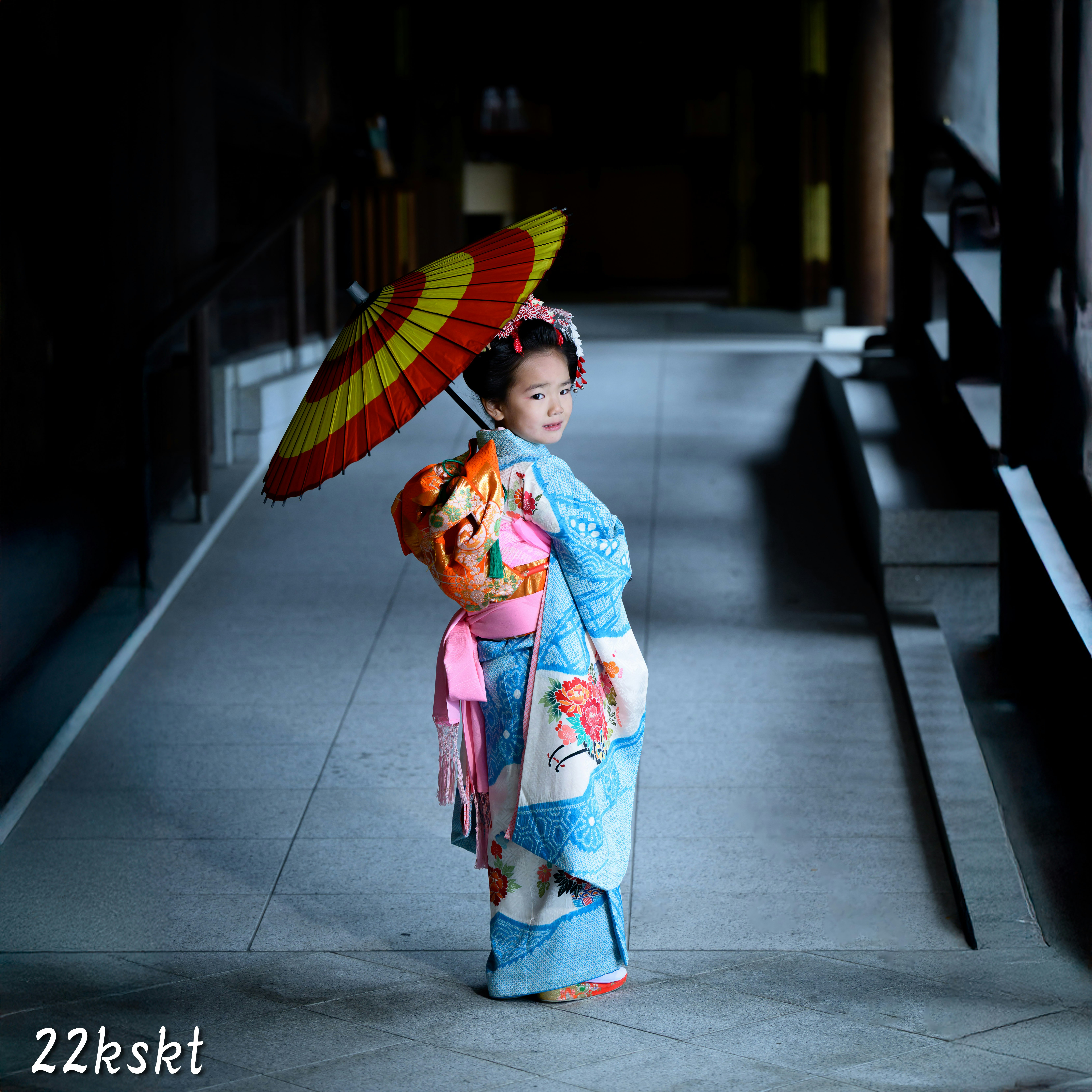 傘を持つ子どもが路地のような通路に立つ