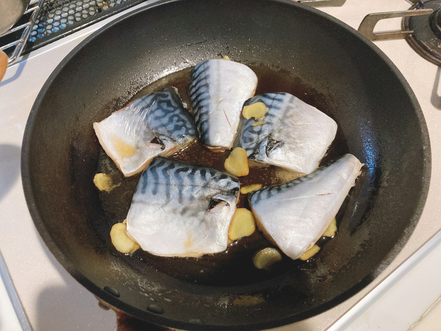 Cá fillet đang nấu trong chảo với lát gừng