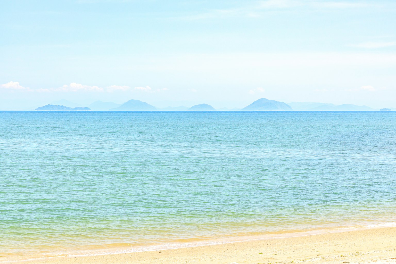 Vista de playa serena con mar azul e islas distantes