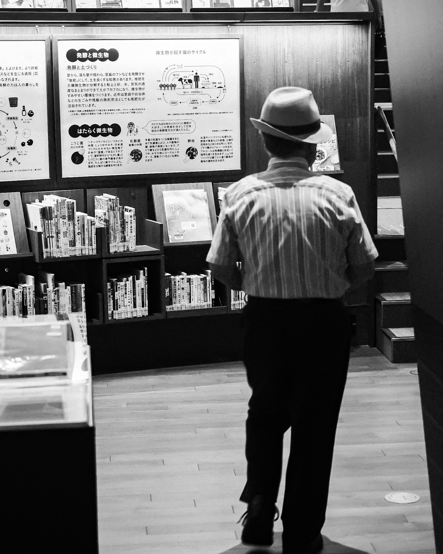 Un uomo con un cappello che cammina tra gli scaffali in una foto in bianco e nero