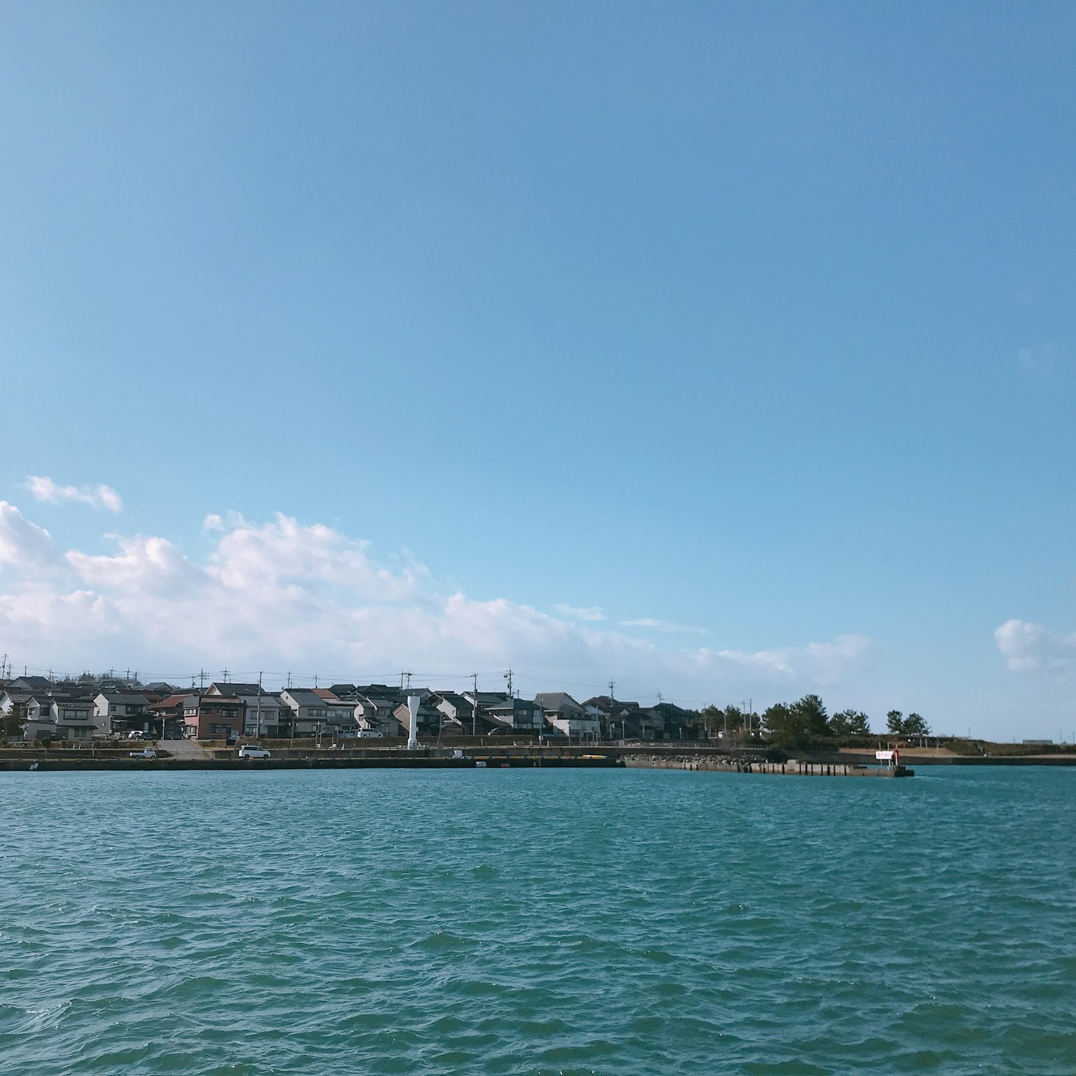 Coastal view featuring blue water and clear sky with residential buildings