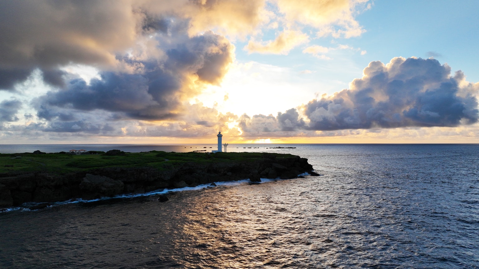 Coastal lighthouse at sunset with dramatic clouds