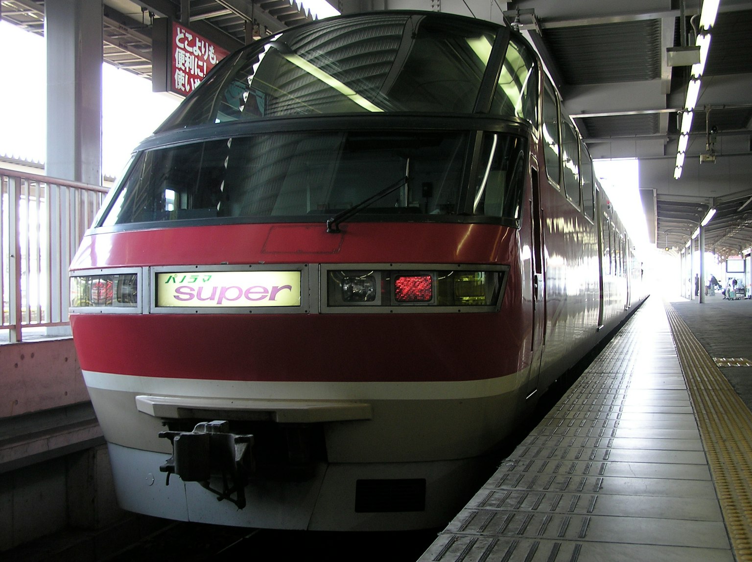 Un tren rojo está detenido en un andén de estación