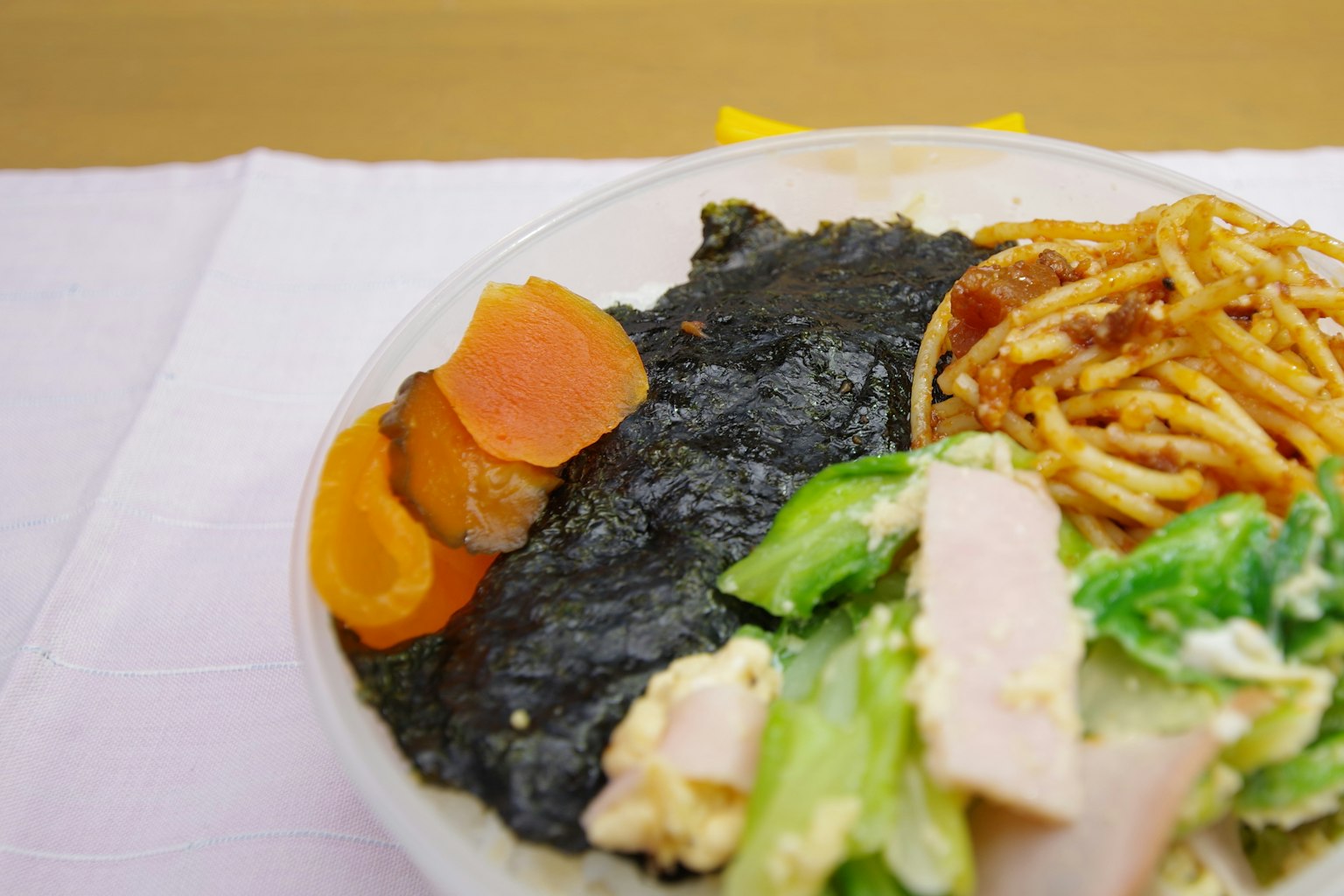 Un plato con alga negra, ensalada, espagueti y zanahorias en rodajas