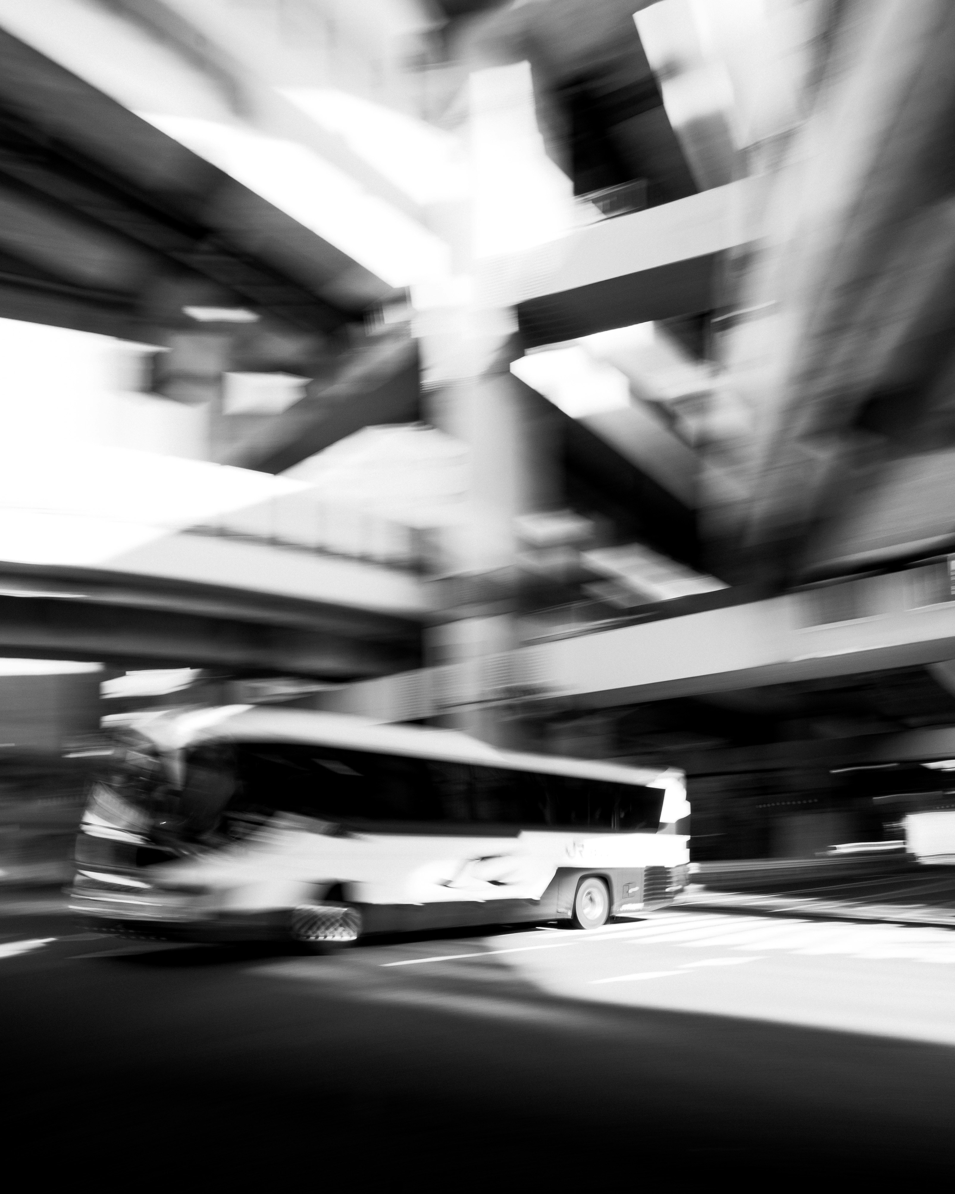 モノクロの街中を走る車と流れるような動きのある風景