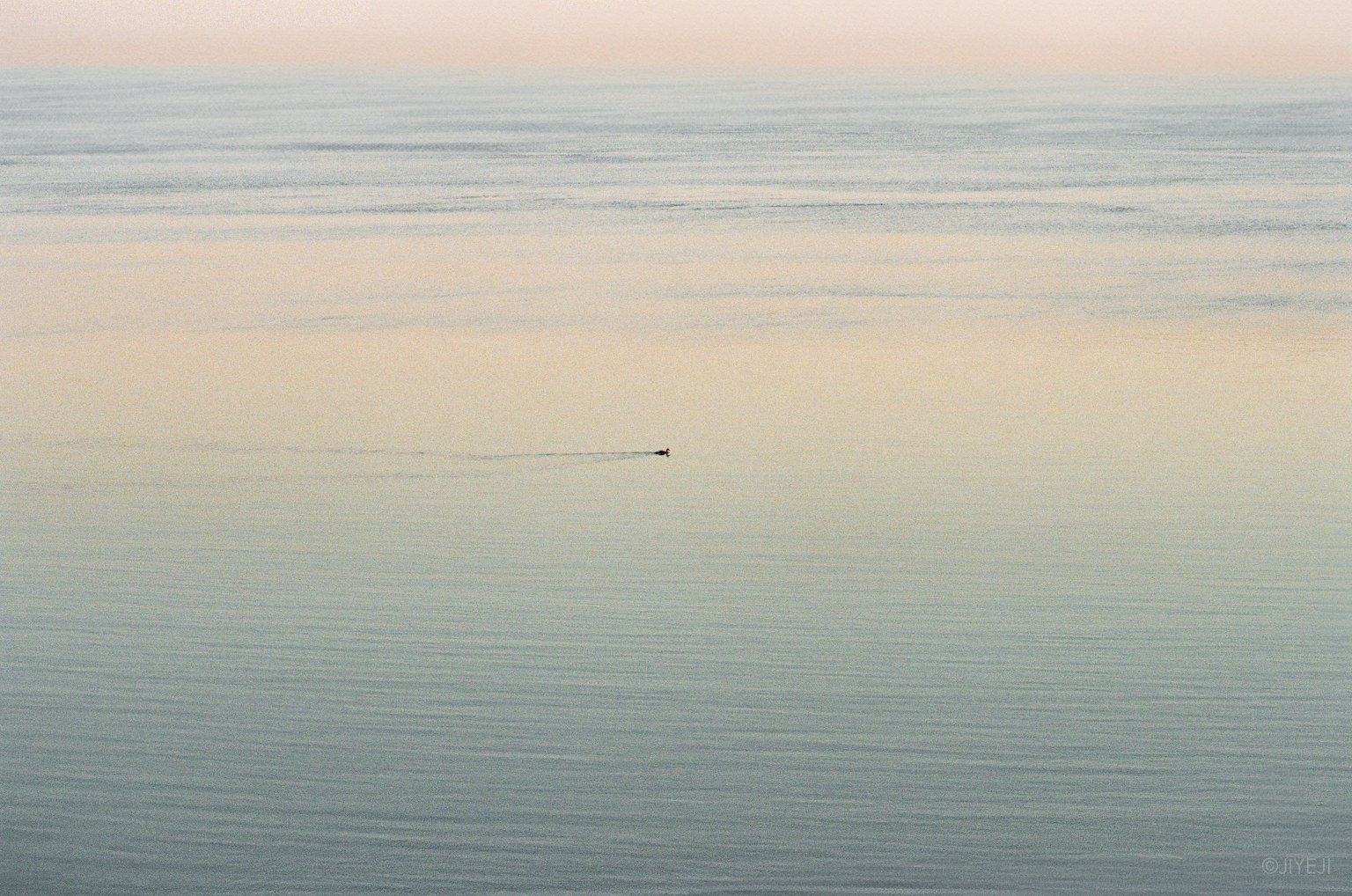 Ein kleines Boot, das auf einem ruhigen Meer bei Sonnenaufgang schwimmt