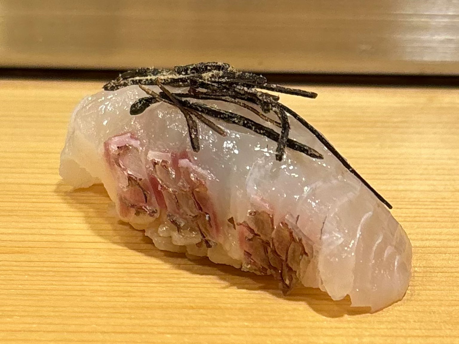 A beautiful piece of sushi topped with seaweed featuring fresh fish