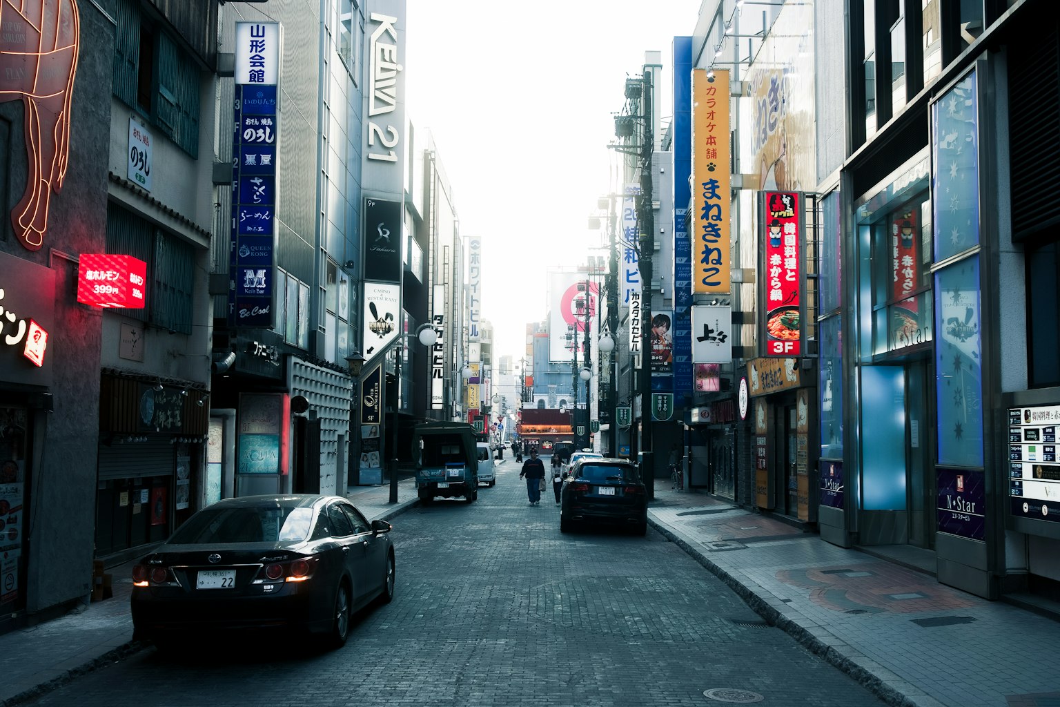 Strada urbana vivace con insegne al neon e auto parcheggiate