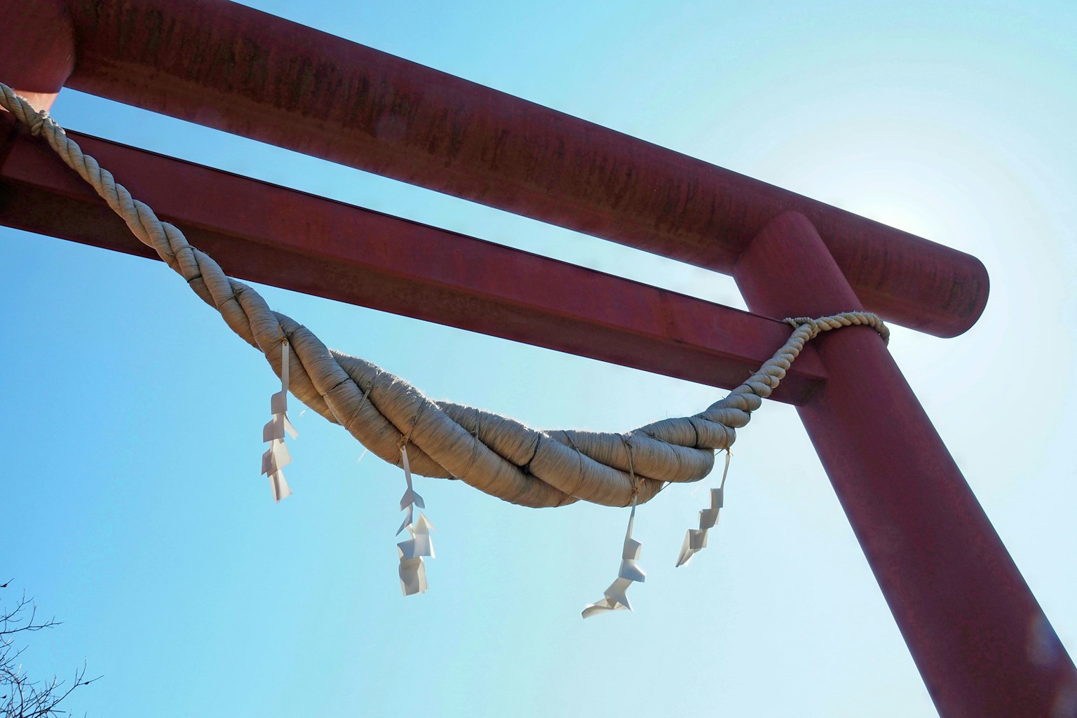 Image d'un torii rouge avec une corde shimenawa