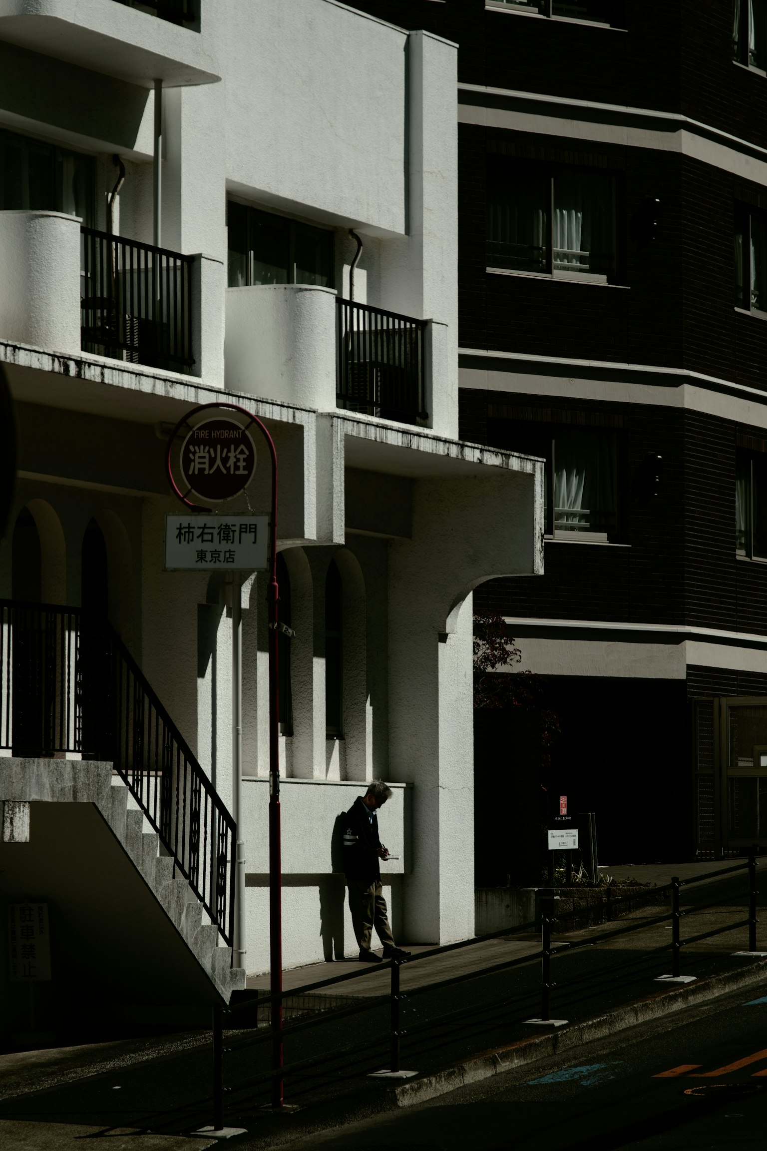 Una persona de pie en una esquina de la calle con edificios blancos y negros contrastantes