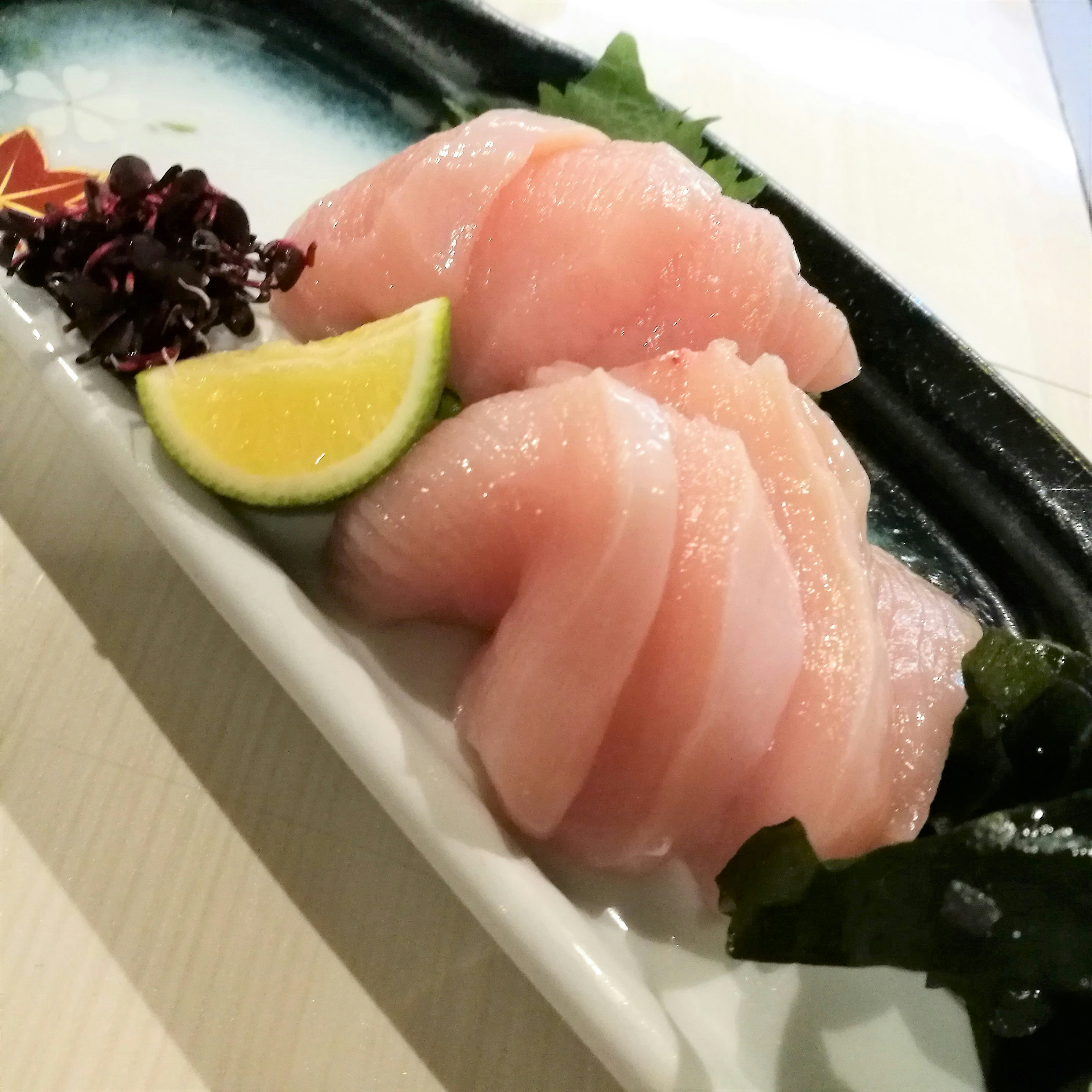 sliced tuna sashimi with lemon garnish