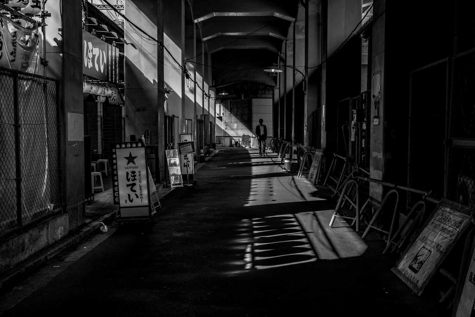 Photo en noir et blanc d'un couloir sombre avec des contrastes frappants de lumière et d'ombre