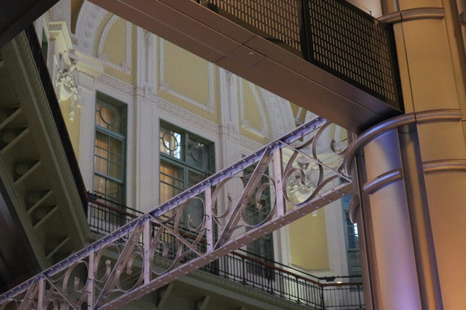 Interior of a building featuring a decorative metal arch and elegant windows