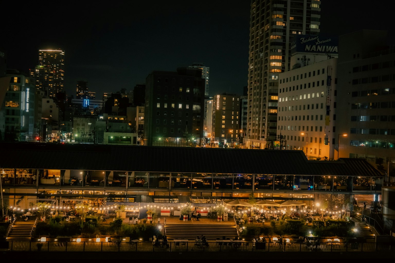 夜間城市景觀，繁忙市場的燈光照亮，背景是摩天大樓