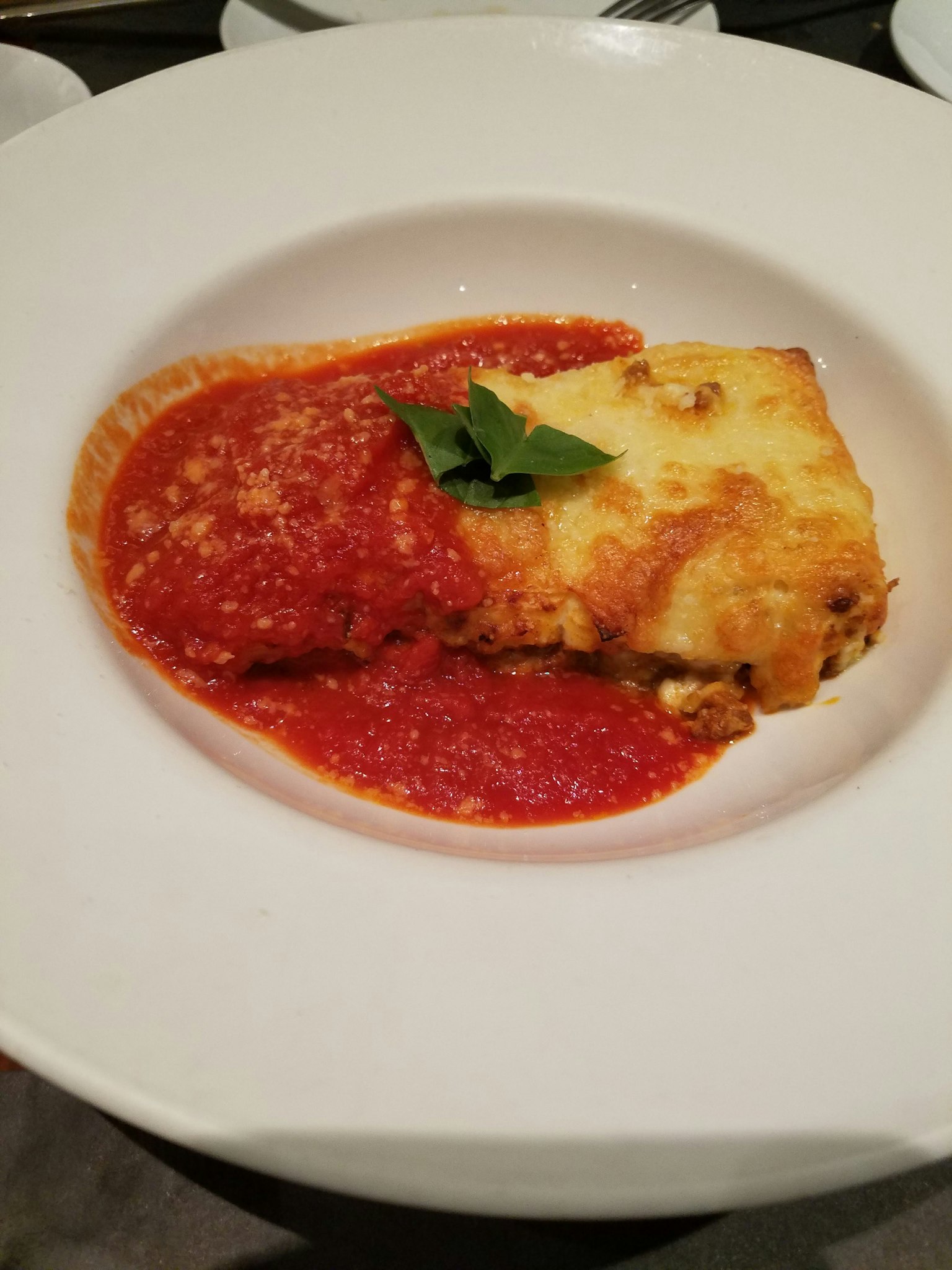 Lasagna served with tomato sauce on a white plate