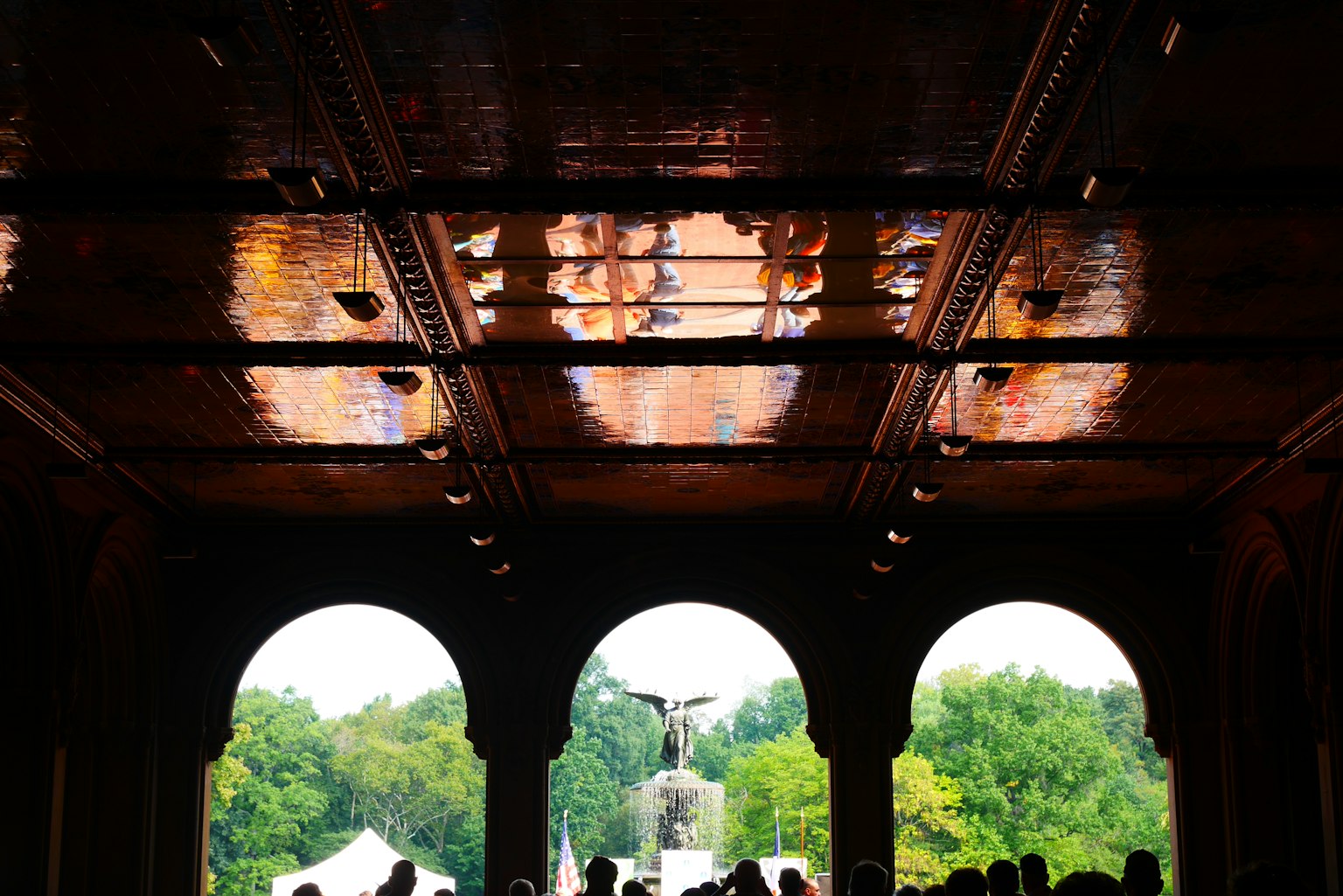 Blick durch einen gewölbten Eingang im Central Park mit Reflexionen an der Decke und grünem Landschaftsbild