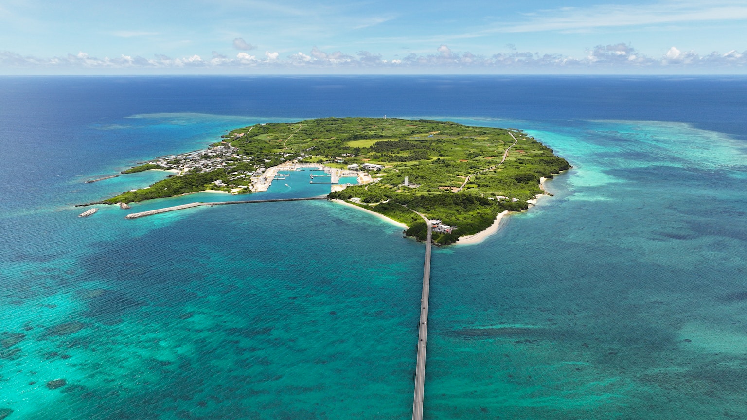 Aerial view of a lush green island surrounded by blue waters and a bridge