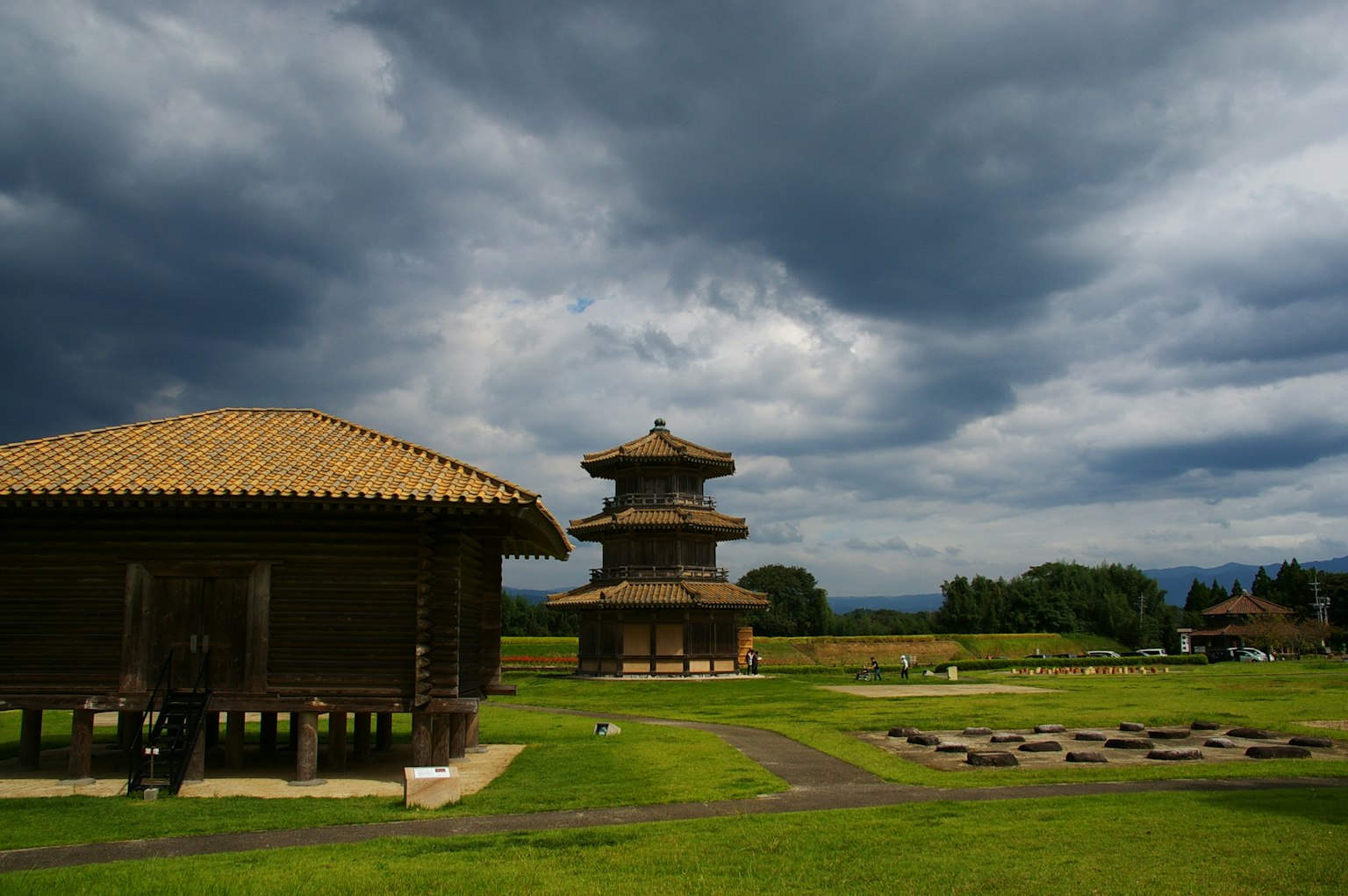 Edifici tradizionali e pagoda in un campo verde sotto un cielo nuvoloso