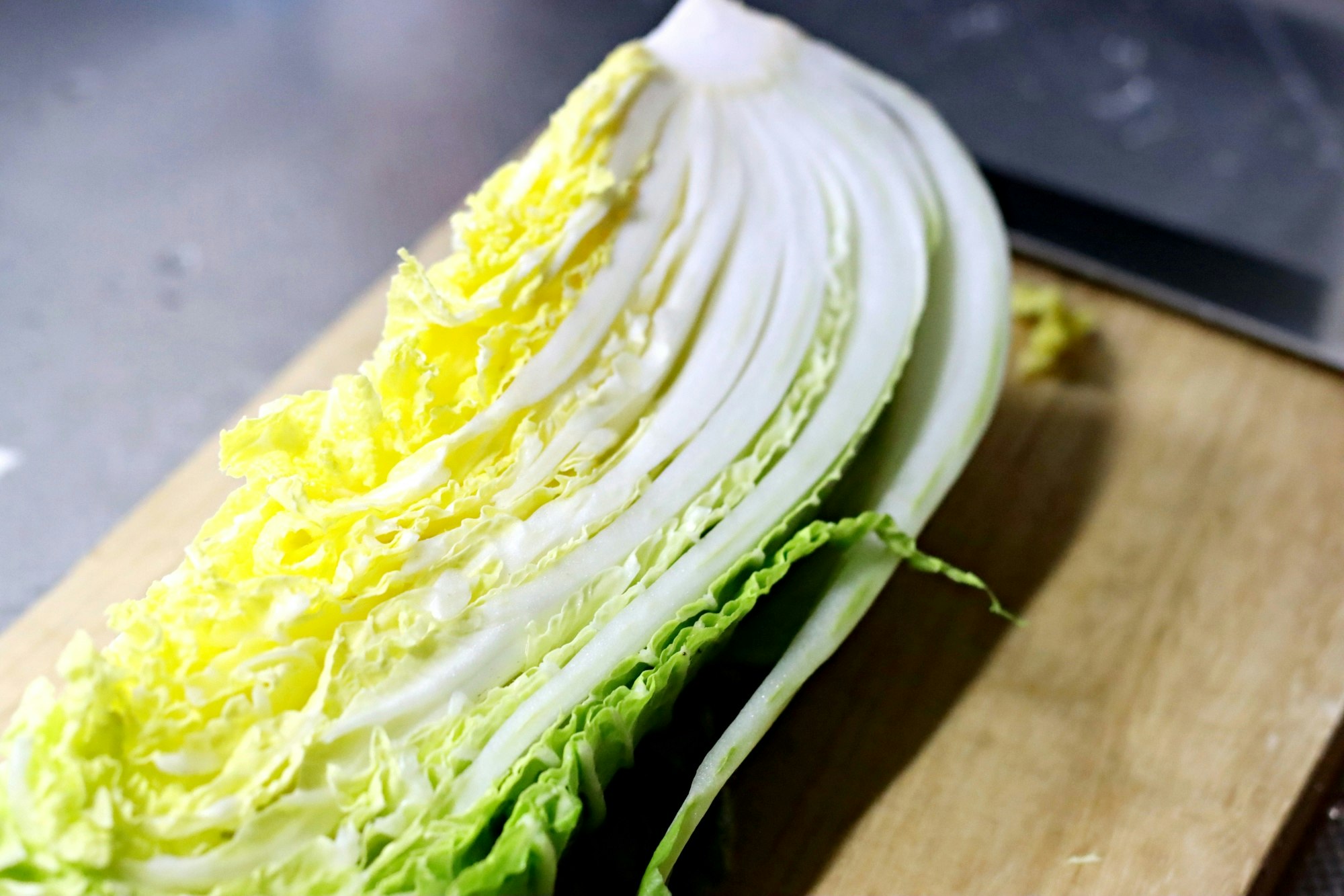 sawi putih (napa cabbage) yang diiris di atas talenan