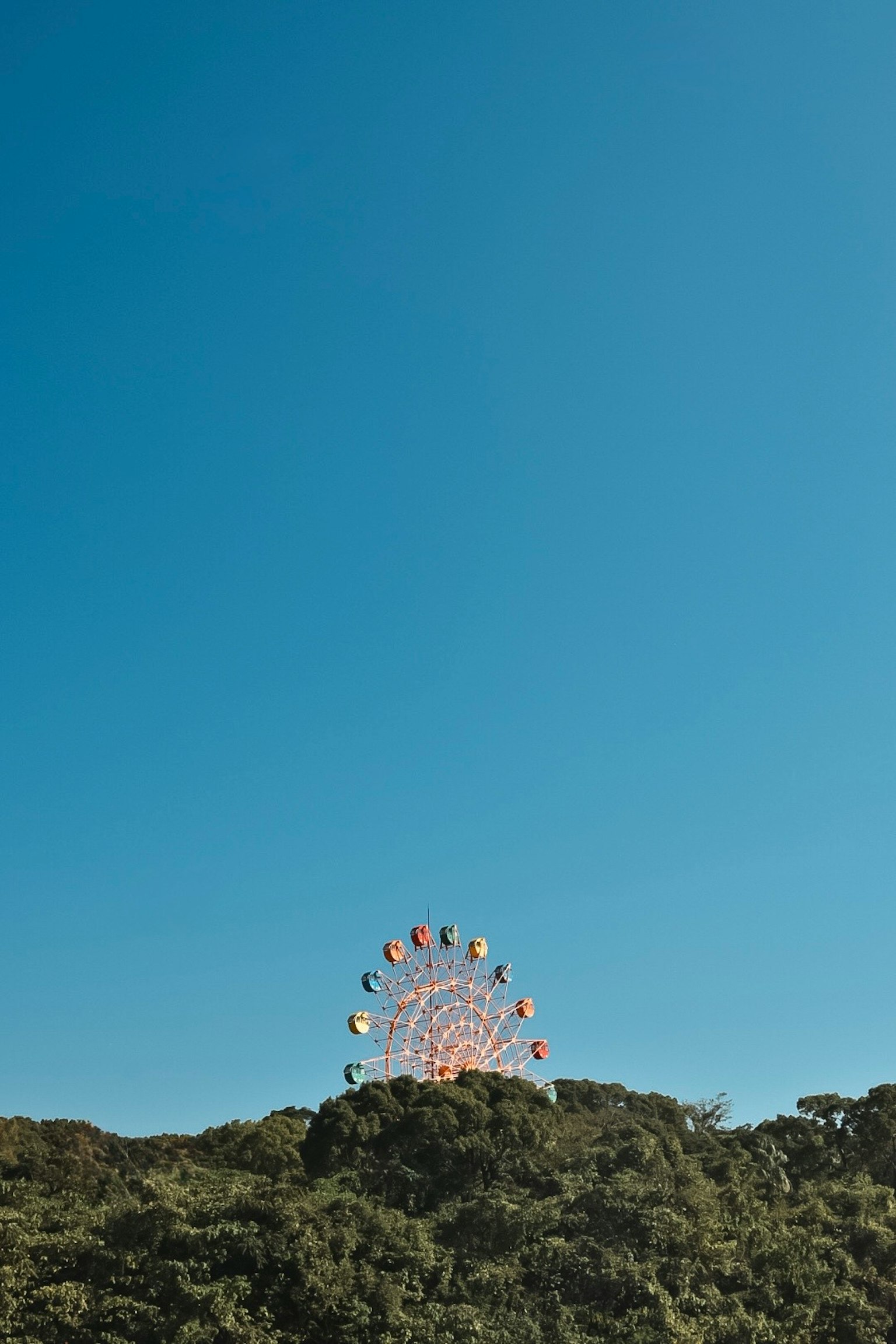 Grande roue partiellement visible sur une colline verte sous un ciel bleu clair